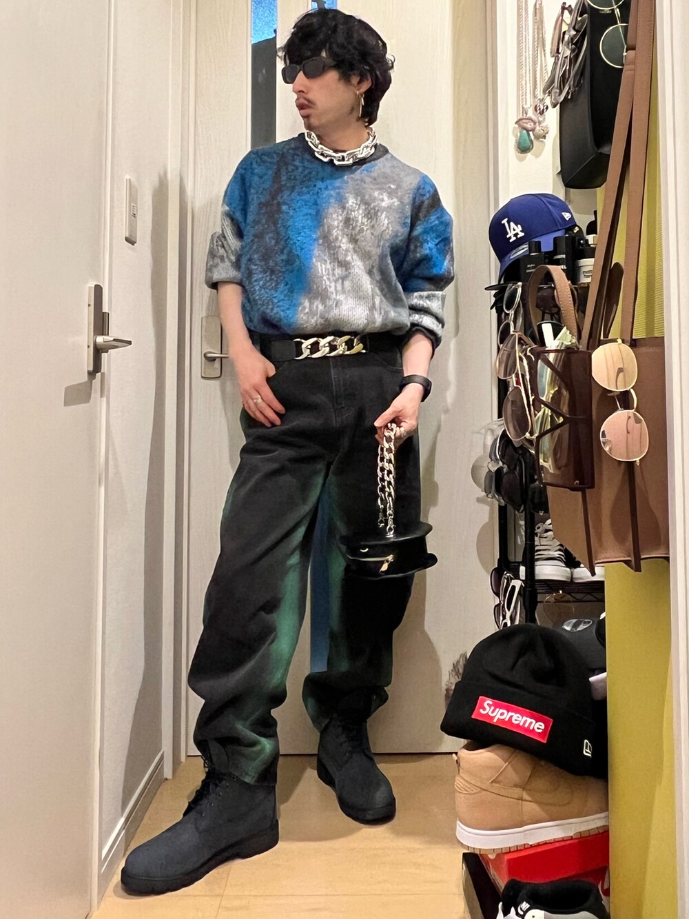 グリーン系のデニムパンツ、ブルー系のブーツ、ブラック系のショルダーバッグを着用したメンズの春コーディネートの2枚目の写真