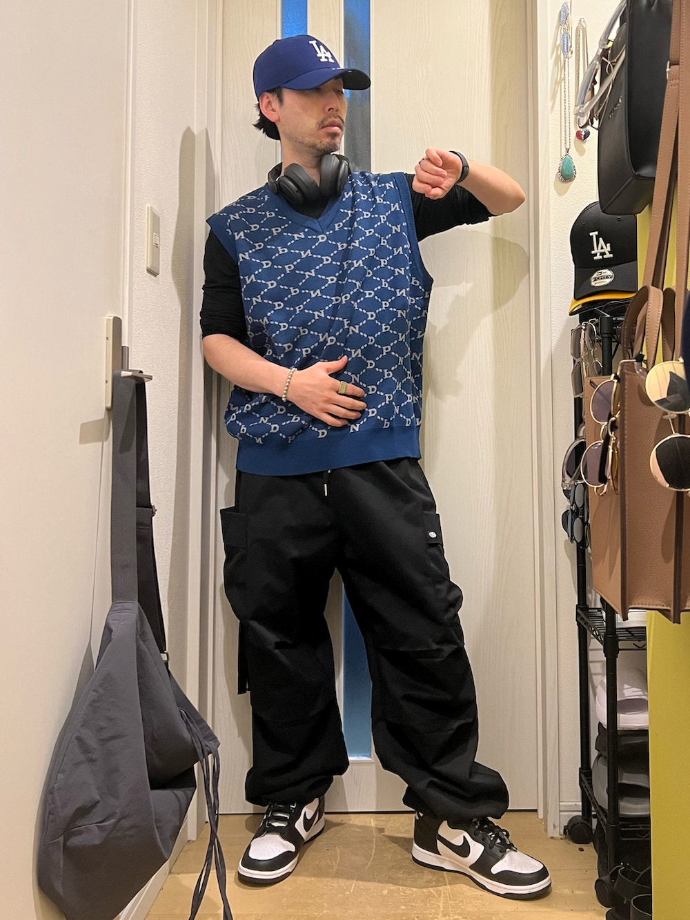 ブラック系のカーゴパンツ、ホワイト系のスニーカー、ブルー系のベストを着用したメンズの春コーディネートの3枚目の写真