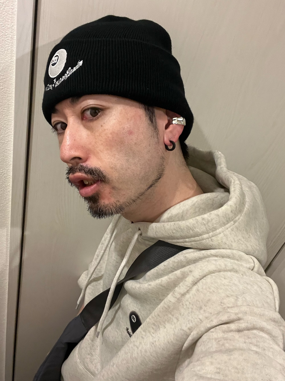 ブラック系のデニムパンツ、ホワイト系のスニーカー、グレー系のショルダーバッグを着用したメンズの夏コーディネートの5枚目の写真