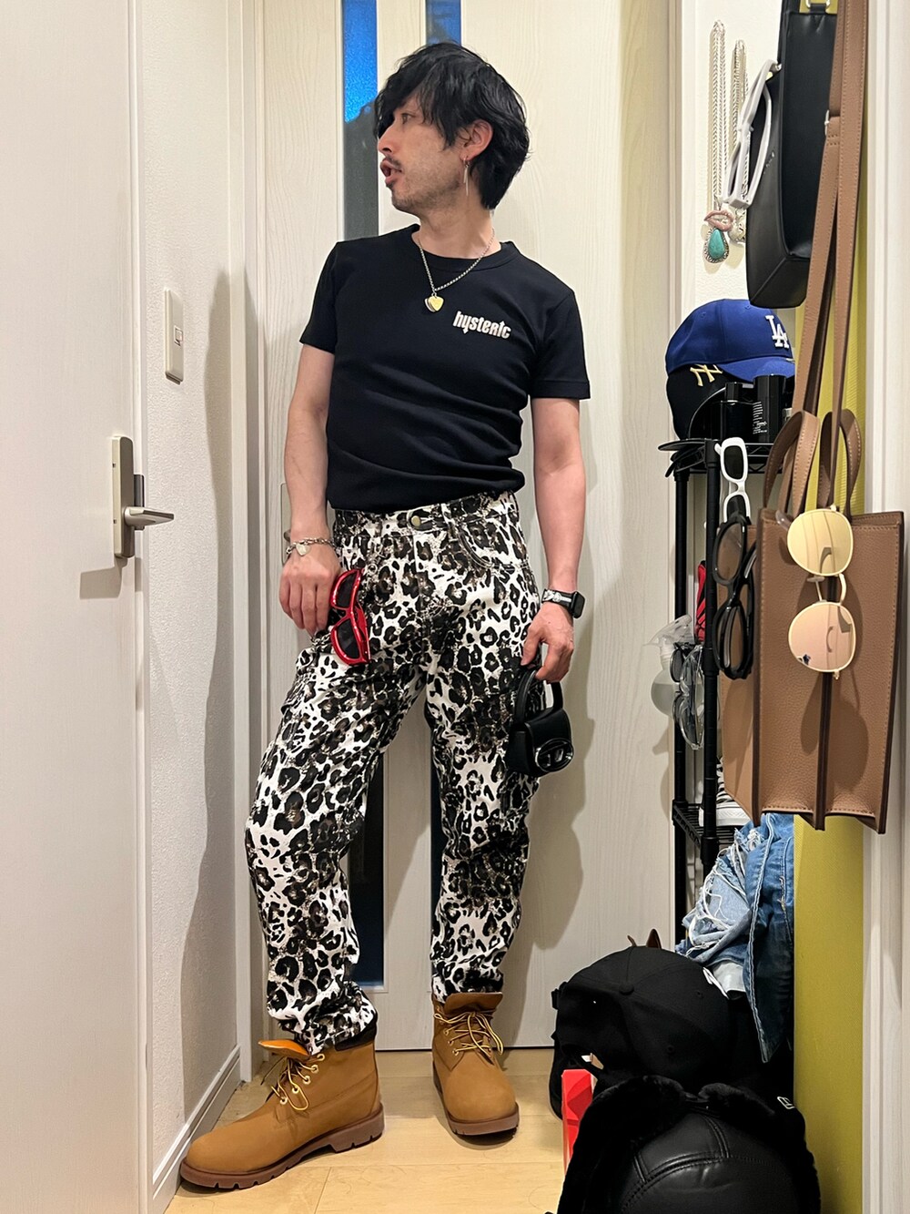 ブラック系のTシャツ/カットソー、ベージュ系のブーツ、ブラック系のショルダーバッグを着用したメンズの夏コーディネートの2枚目の写真