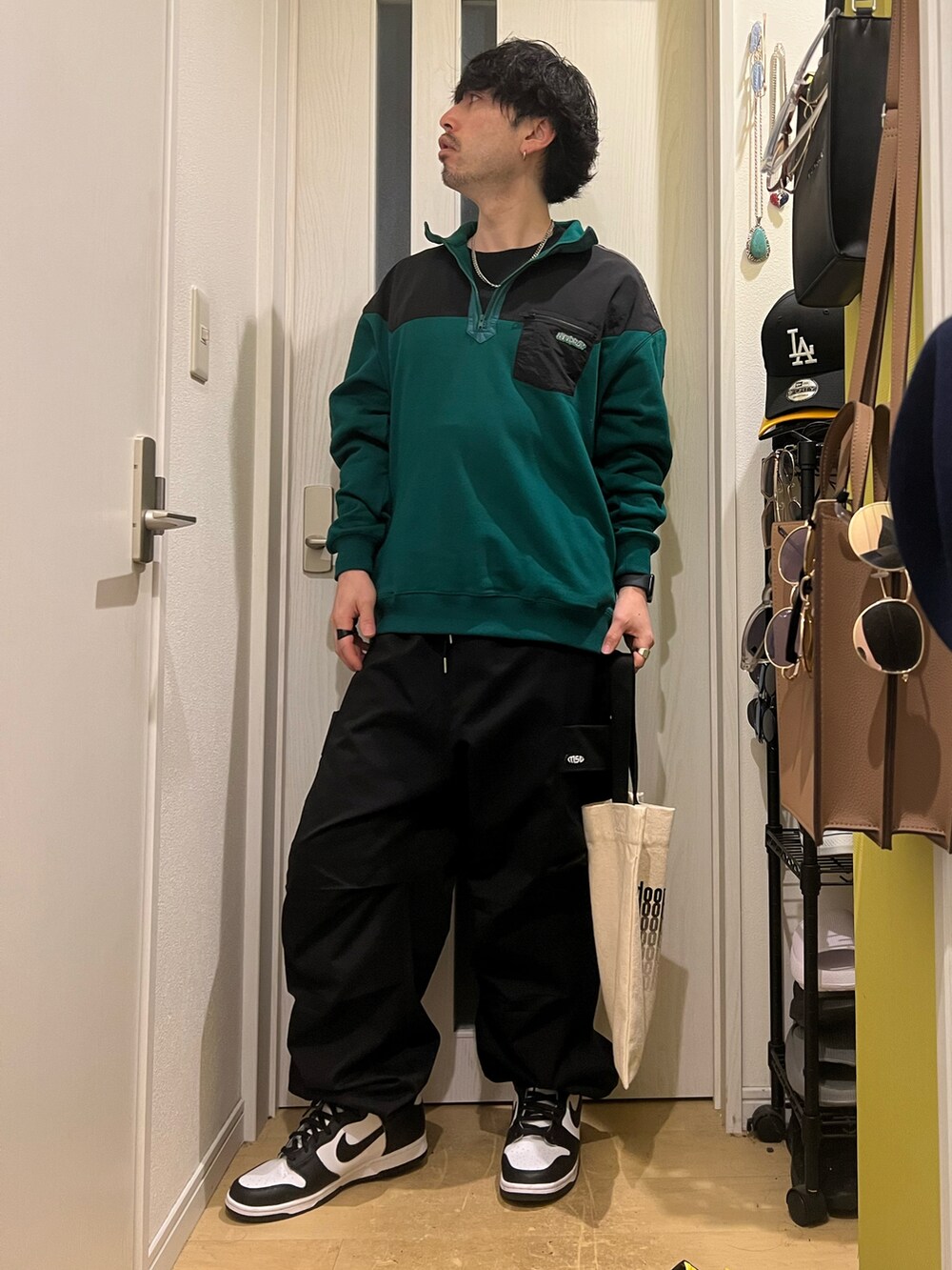 グリーン系のスウェット、ブラック系のカーゴパンツ、ホワイト系のトートバッグを着用したメンズの春コーディネートの3枚目の写真