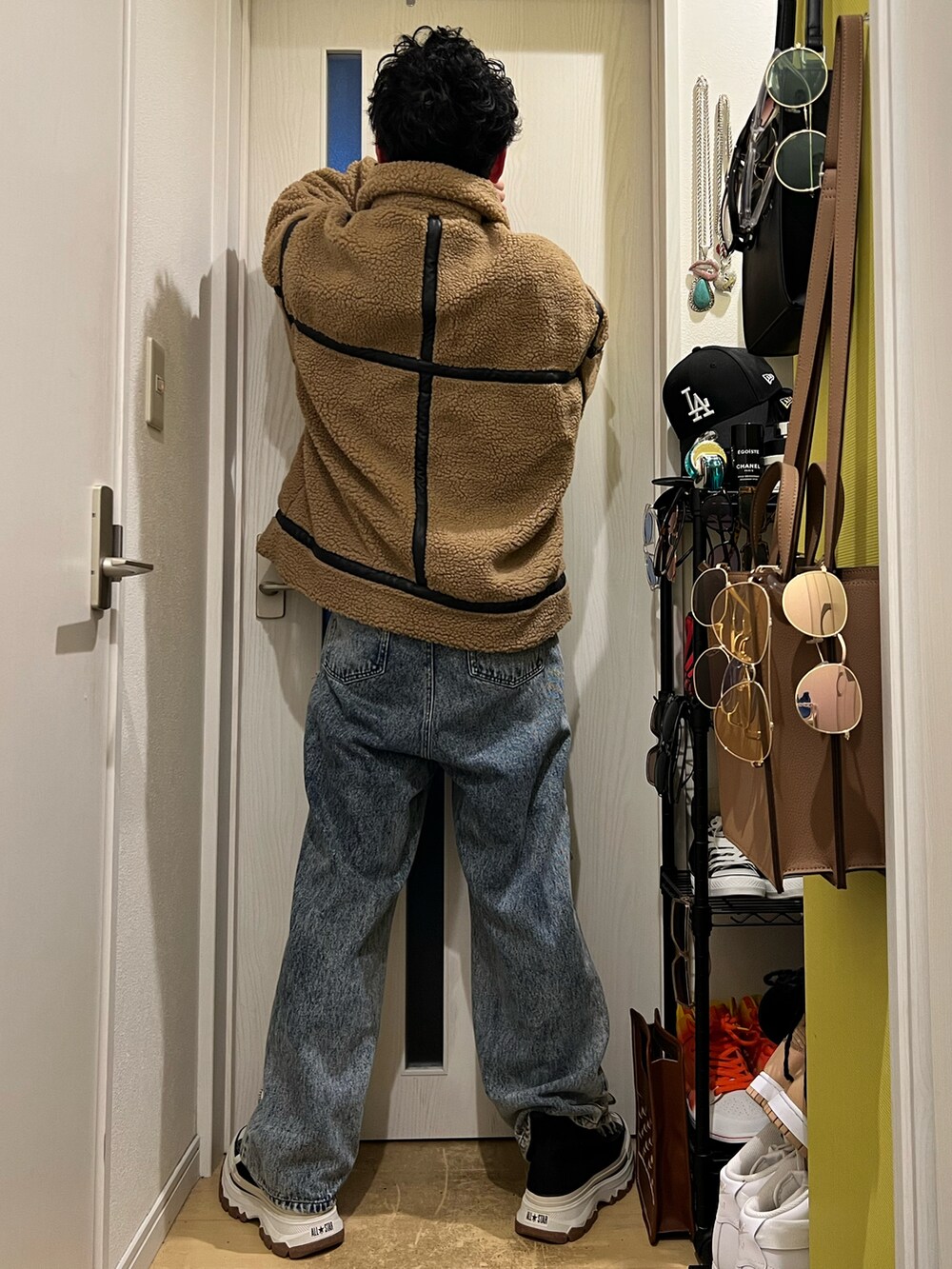 ブラウン系のハンドバッグ、ブルー系のデニムパンツ、ブラック系のスニーカーを着用したメンズの冬コーディネートの4枚目の写真