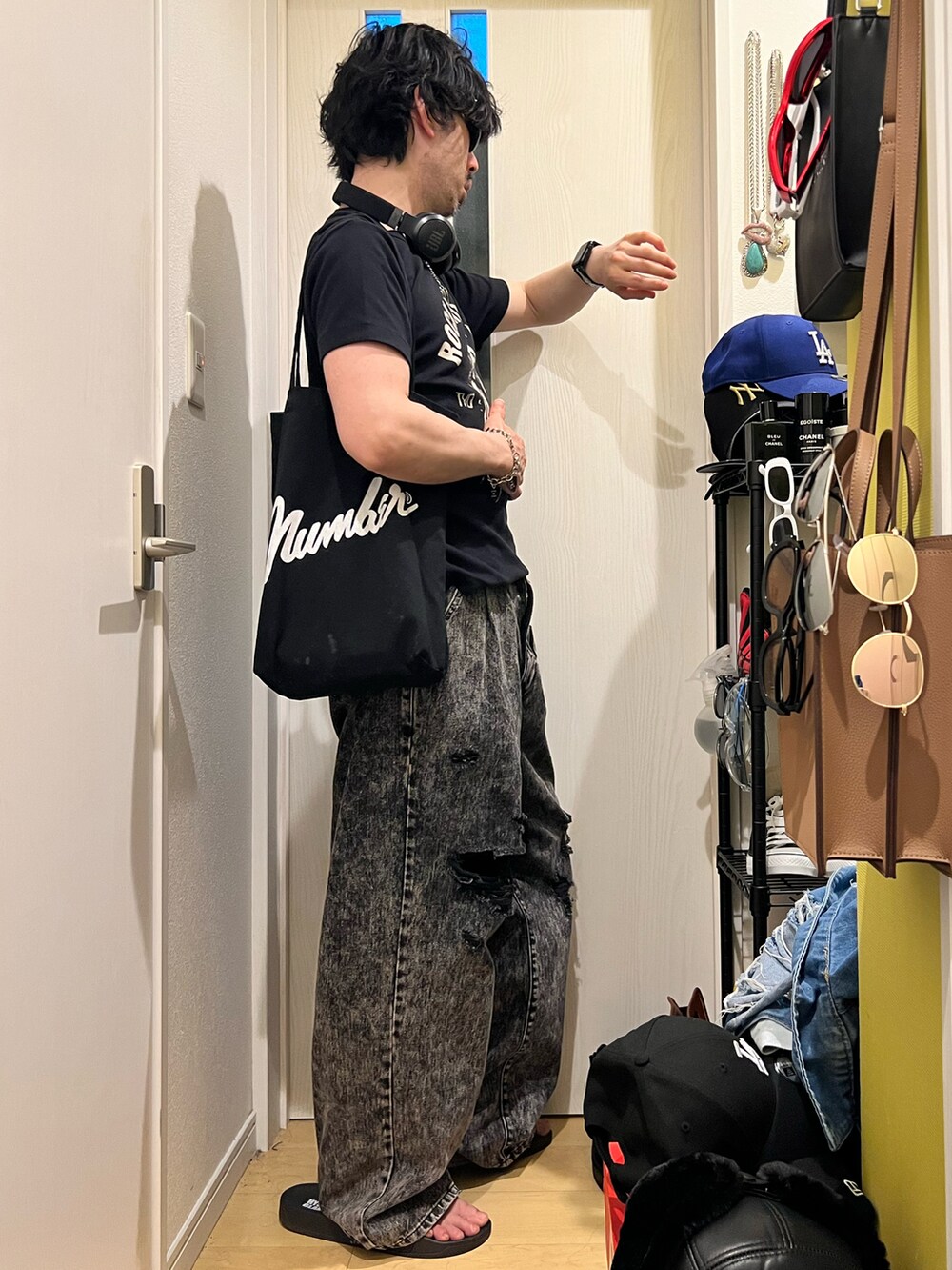 ブラック系のデニムパンツ、ブラック系のサンダル、ブラック系のトートバッグを着用したメンズの秋コーディネートの2枚目の写真