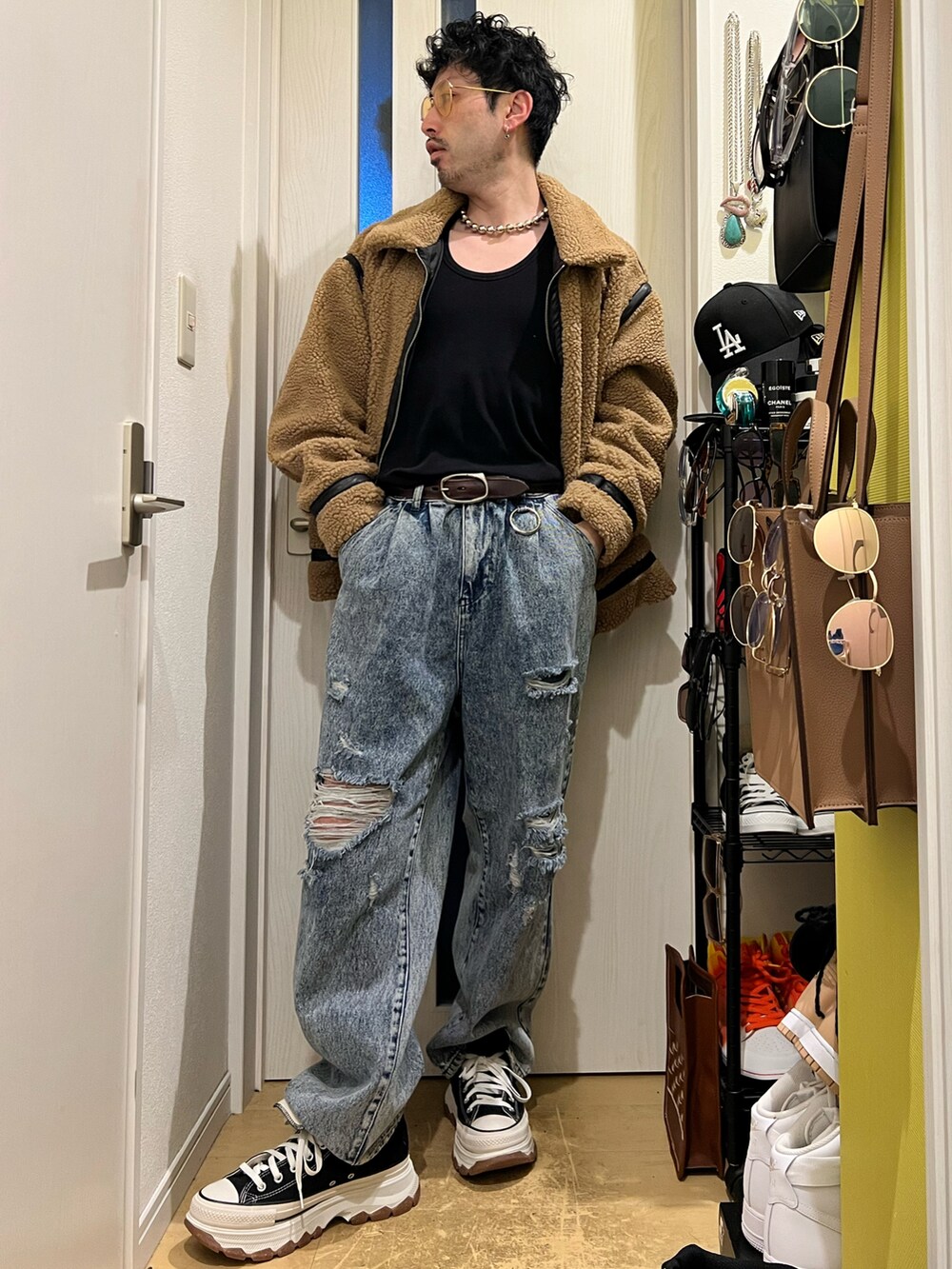 ブラウン系のハンドバッグ、ブルー系のデニムパンツ、ブラック系のスニーカーを着用したメンズの冬コーディネートの2枚目の写真