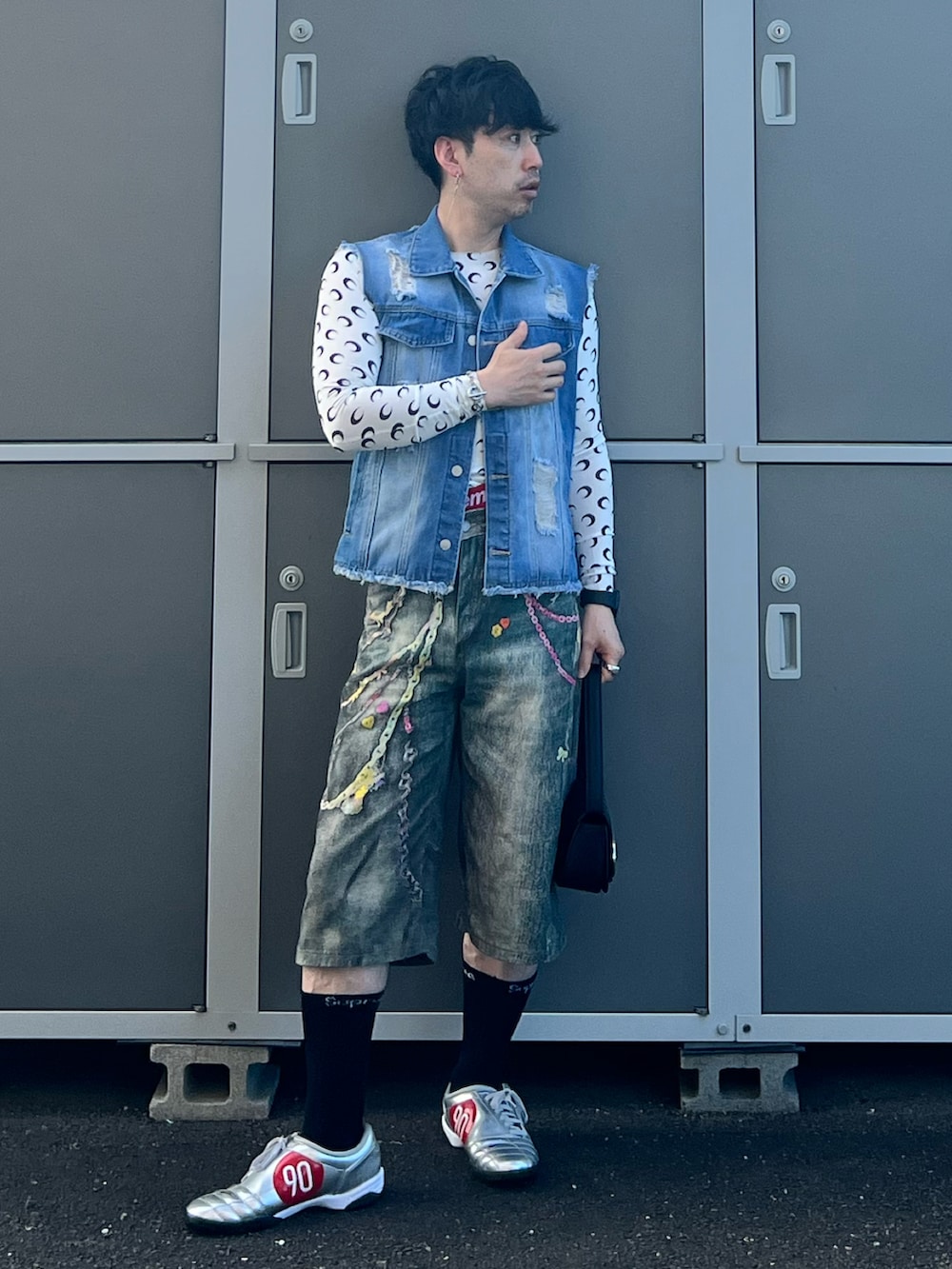 ブルー系のデニムパンツ、シルバー系のスニーカー、ブラック系のショルダーバッグを着用したメンズの夏コーディネートの2枚目の写真