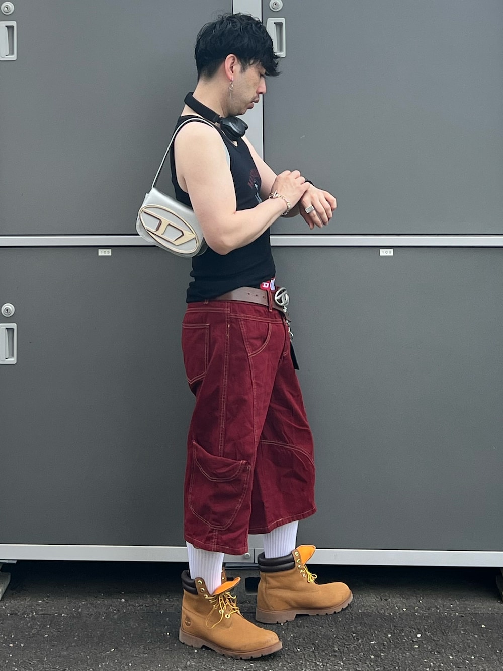 ブラック系のキャミソール、レッド系のデニムパンツ、シルバー系のショルダーバッグを着用したメンズの夏コーディネートの2枚目の写真