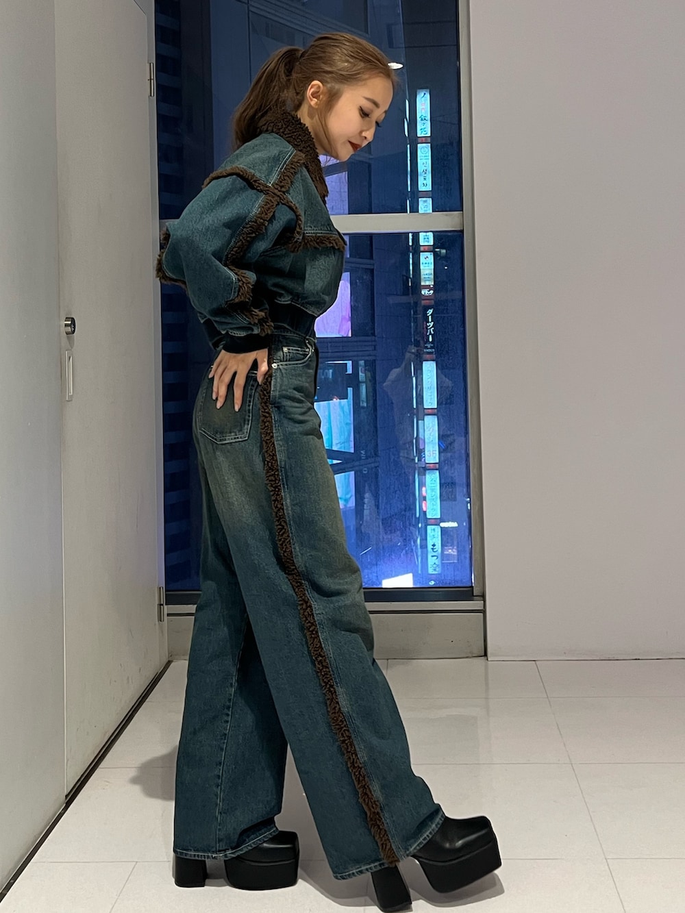 ブルー系のブルゾン、ブルー系のデニムパンツ、ブラック系のブーツを着用したレディースの秋コーディネートの2枚目の写真