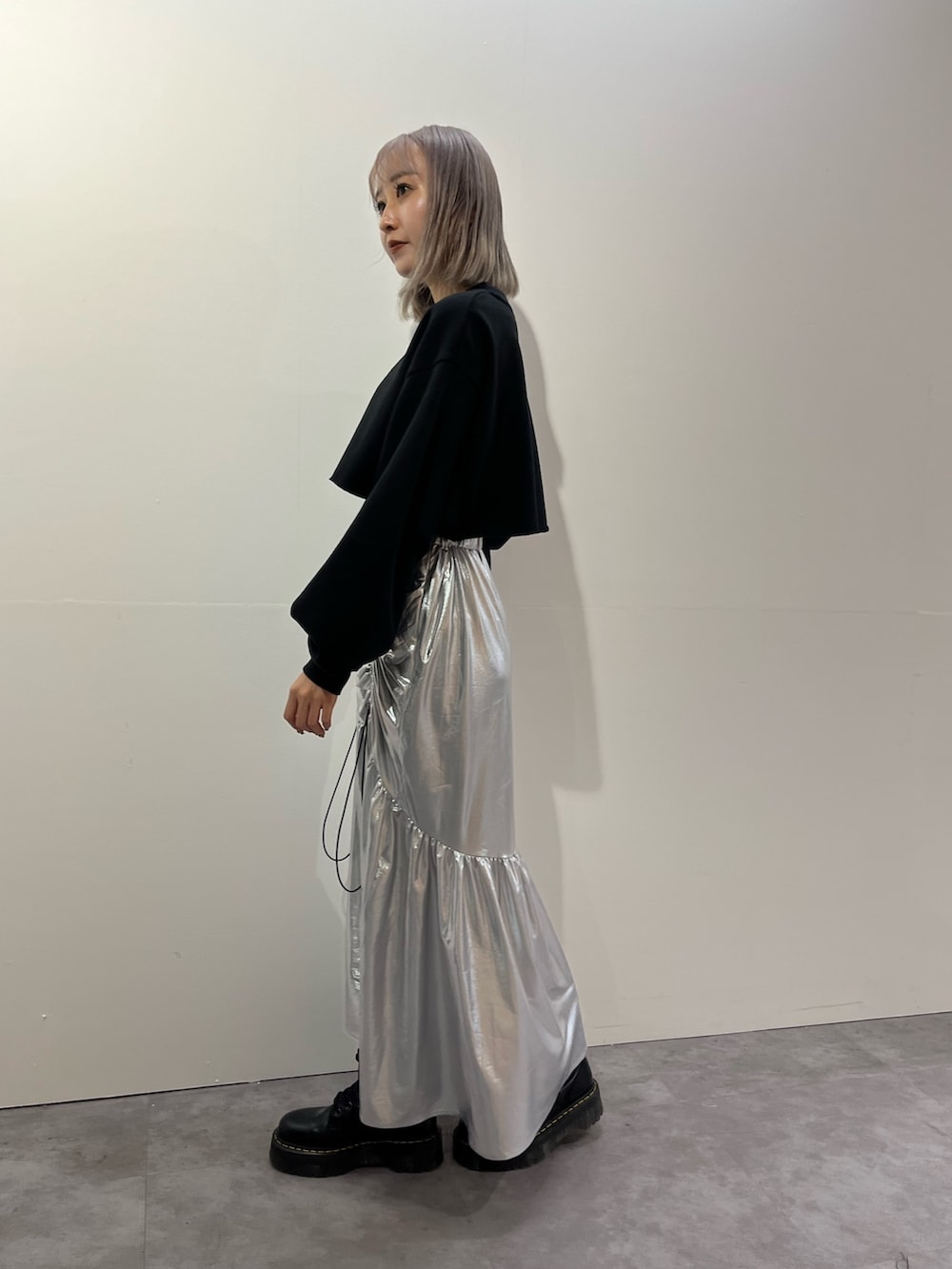 シルバー系のスカート、ホワイト系のスウェットを着用したレディースの秋コーディネートの2枚目の写真