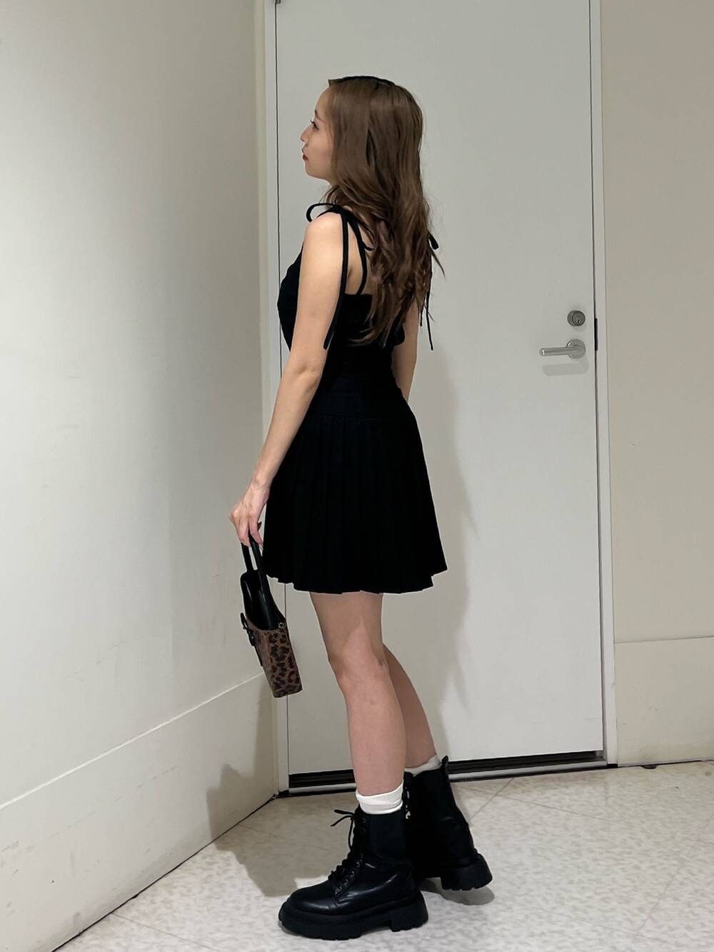 ブラウン系のハンドバッグ、ブラック系のブーツ、ブラック系のワンピースを着用したレディースの夏コーディネートの2枚目の写真