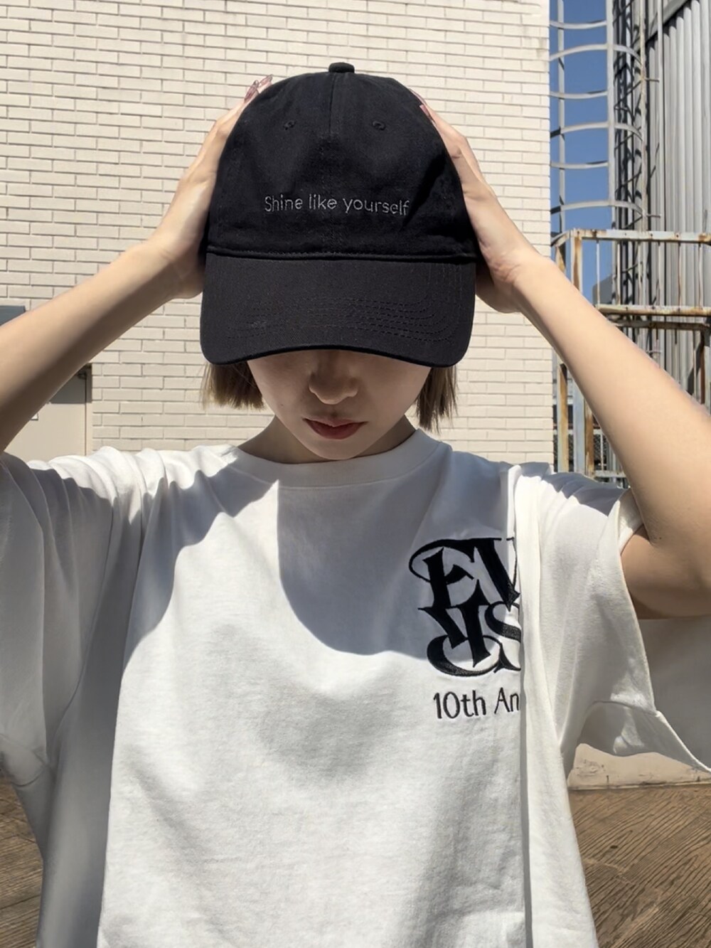ホワイト系のTシャツ/カットソー、ブラック系のブーツ、ブラック系のキャップを着用したレディースの春コーディネートの4枚目の写真