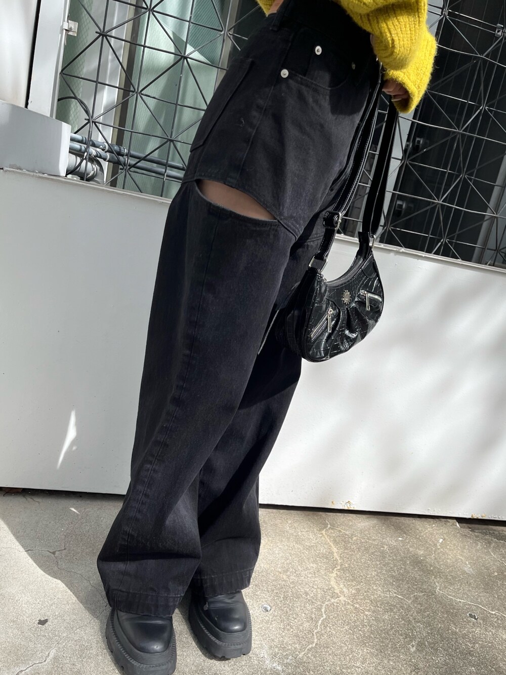 ブラック系のショルダーバッグ、ブラック系のデニムパンツ、イエロー系のニット/セーターを着用したレディースの秋コーディネートの7枚目の写真