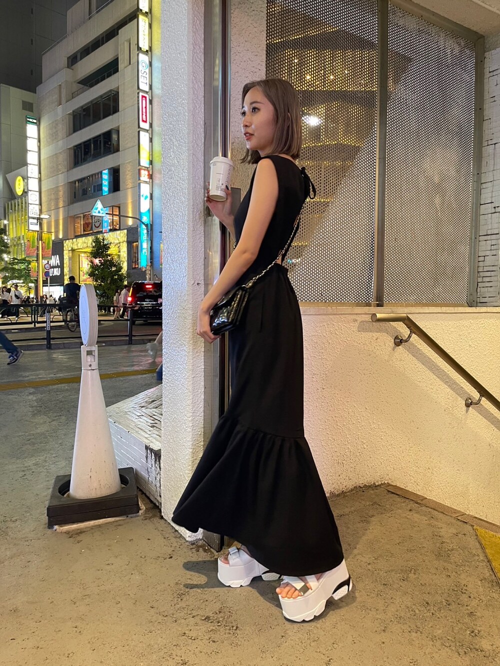 ブラック系のワンピース、ブラック系のショルダーバッグ、ホワイト系のサンダルを着用したレディースの夏コーディネートの4枚目の写真