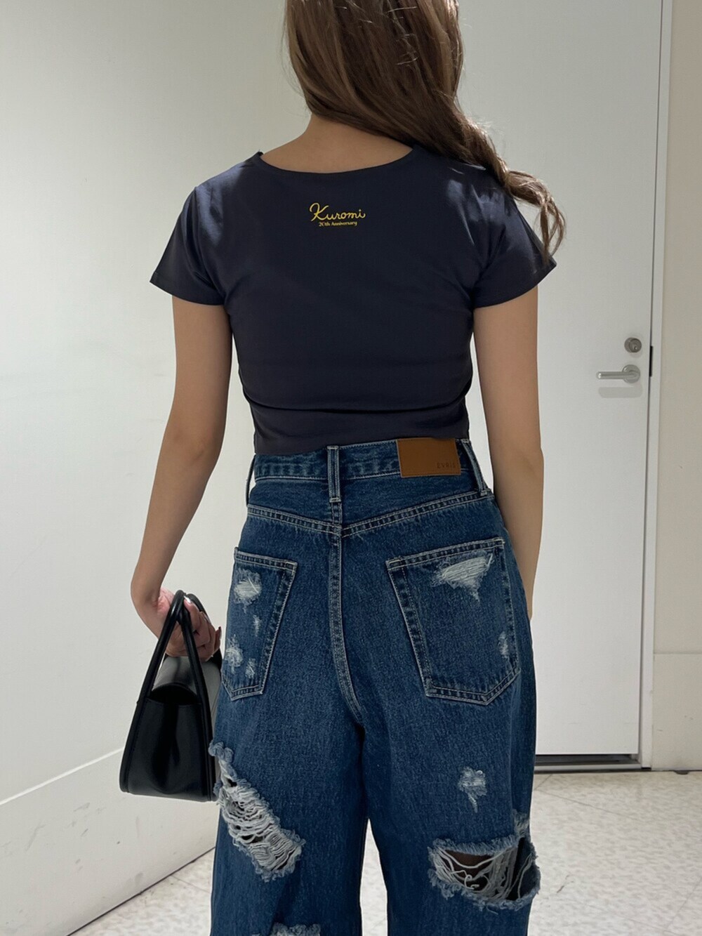 ブラック系のブーツ、ブルー系のデニムパンツ、ブラック系のハンドバッグを着用したレディースの春コーディネートの5枚目の写真