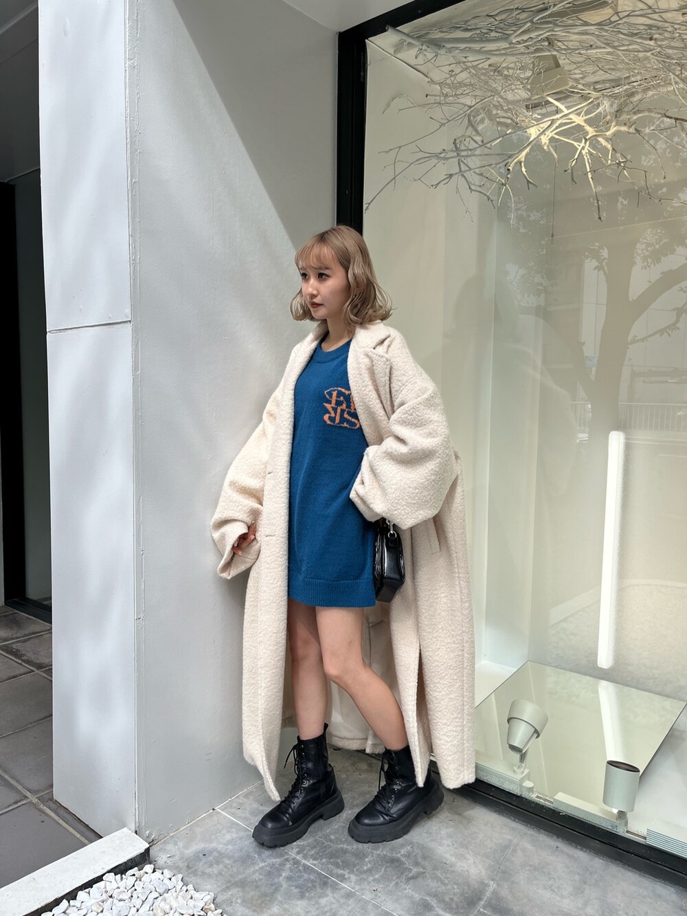 シルバー系のショルダーバッグ、ホワイト系のブーツ、ブルー系のニット/セーターを着用したレディースの秋コーディネートの5枚目の写真