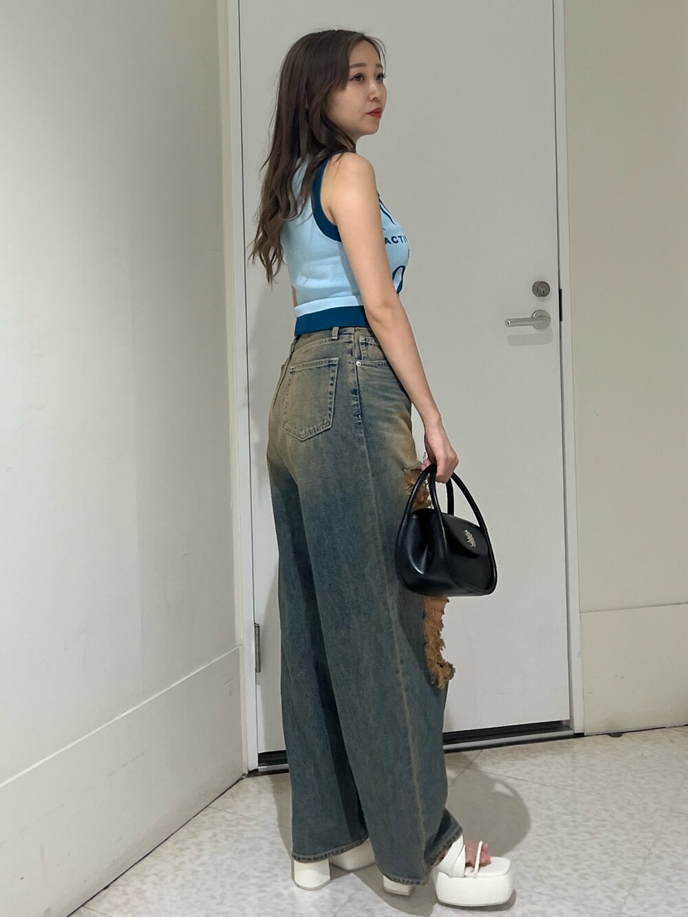 ブラック系のハンドバッグ、ブルー系のデニムパンツ、ブルー系のニット/セーターを着用したレディースの夏コーディネートの4枚目の写真