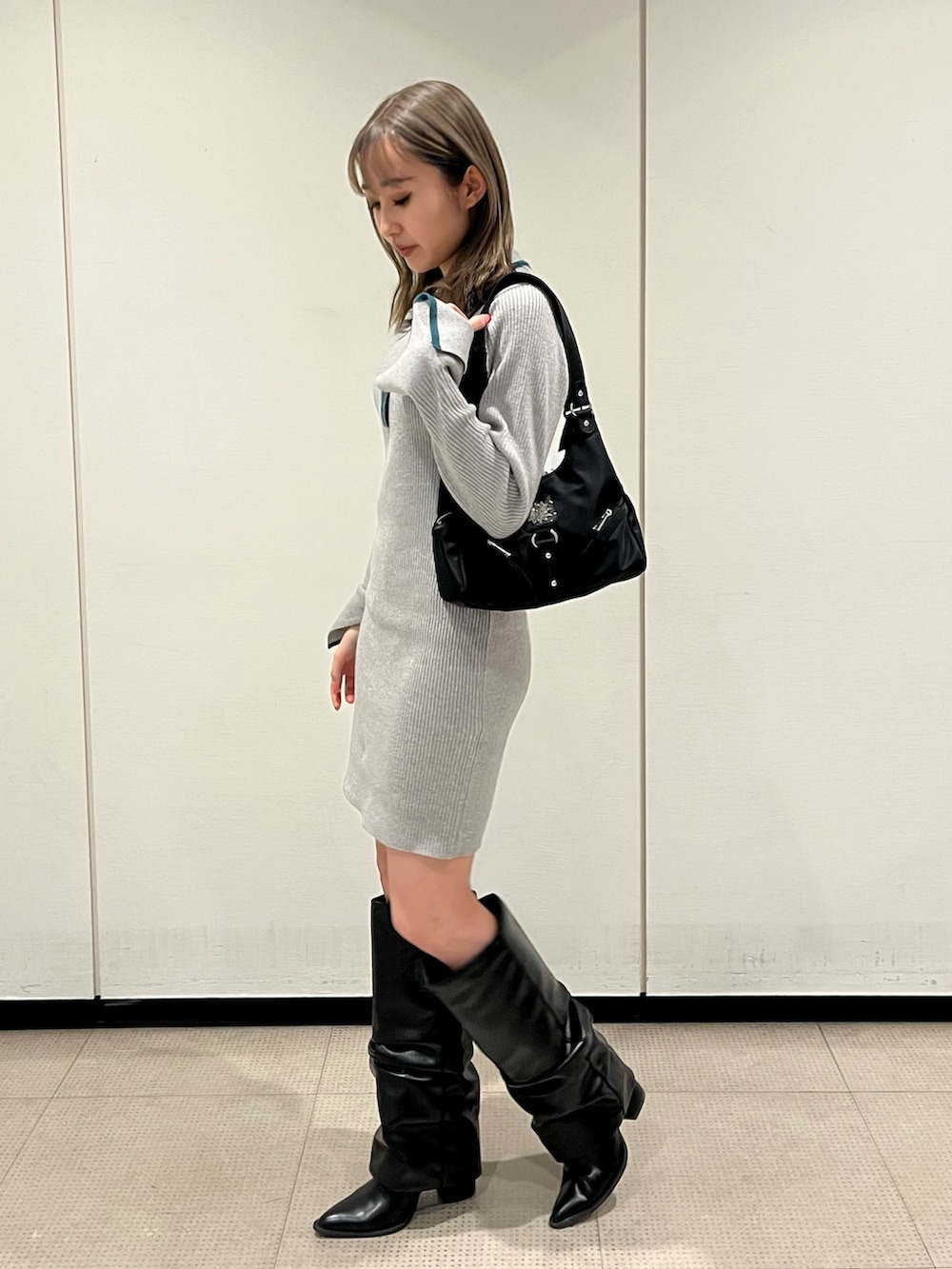 ブラック系のブーツ、グレー系のワンピース、ブラック系のハンドバッグを着用したレディースの冬コーディネートの4枚目の写真