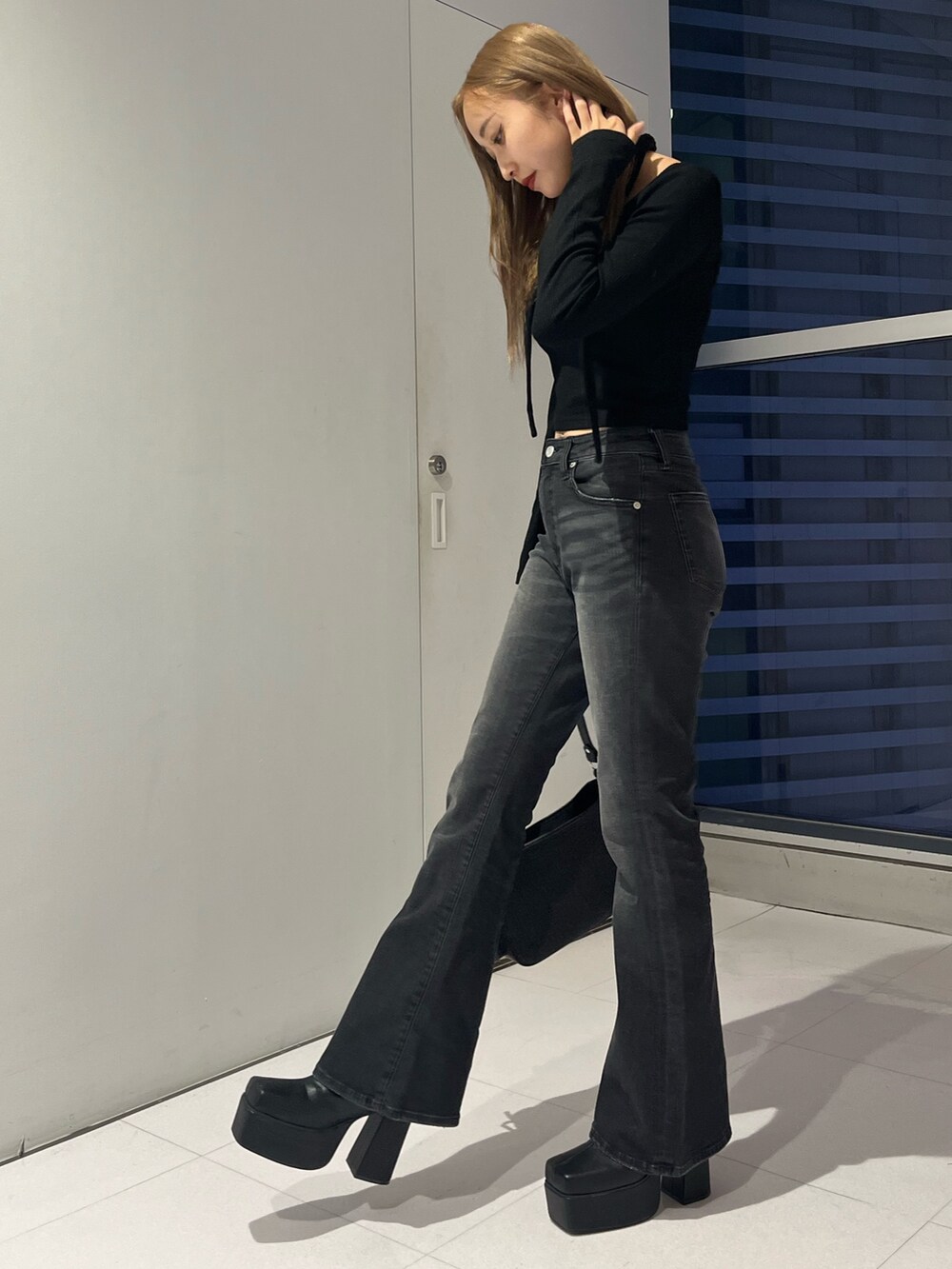 ブラック系のデニムパンツ、ブラック系のハンドバッグ、ブラック系のブーツを着用したレディースの秋コーディネートの2枚目の写真