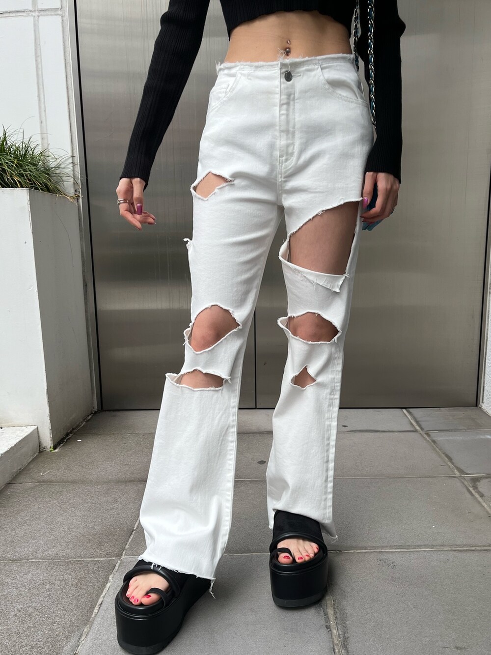 グリーン系のニット/セーター、ブラック系のデニムパンツ、ブラック系のショルダーバッグを着用したレディースの春コーディネートの5枚目の写真