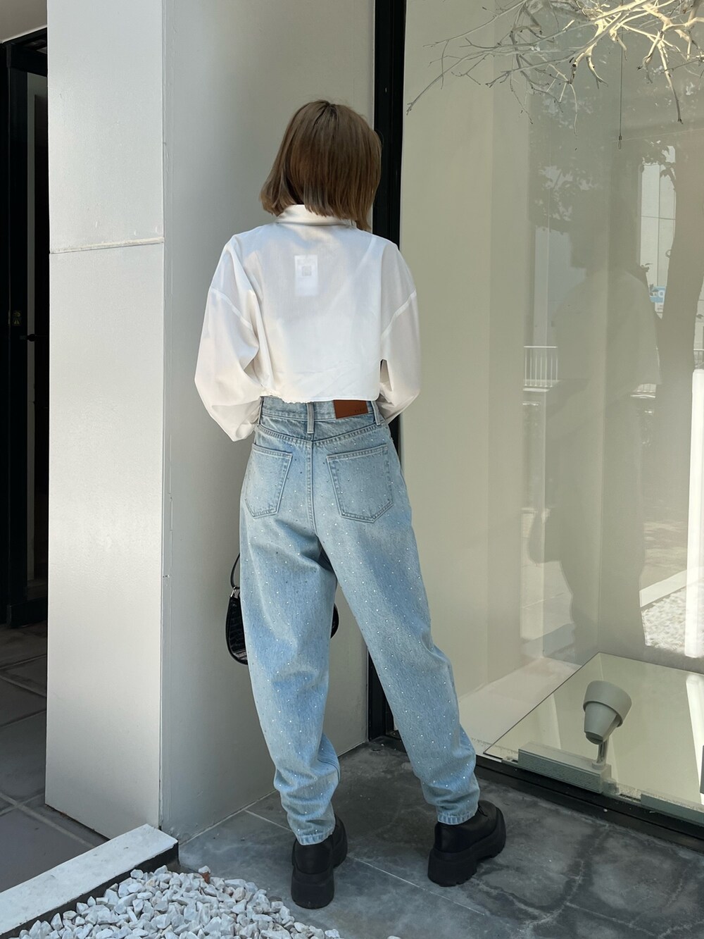 ホワイト系のシャツ/ブラウス、ブルー系のデニムパンツ、ブラック系のショルダーバッグを着用したレディースの秋コーディネートの4枚目の写真