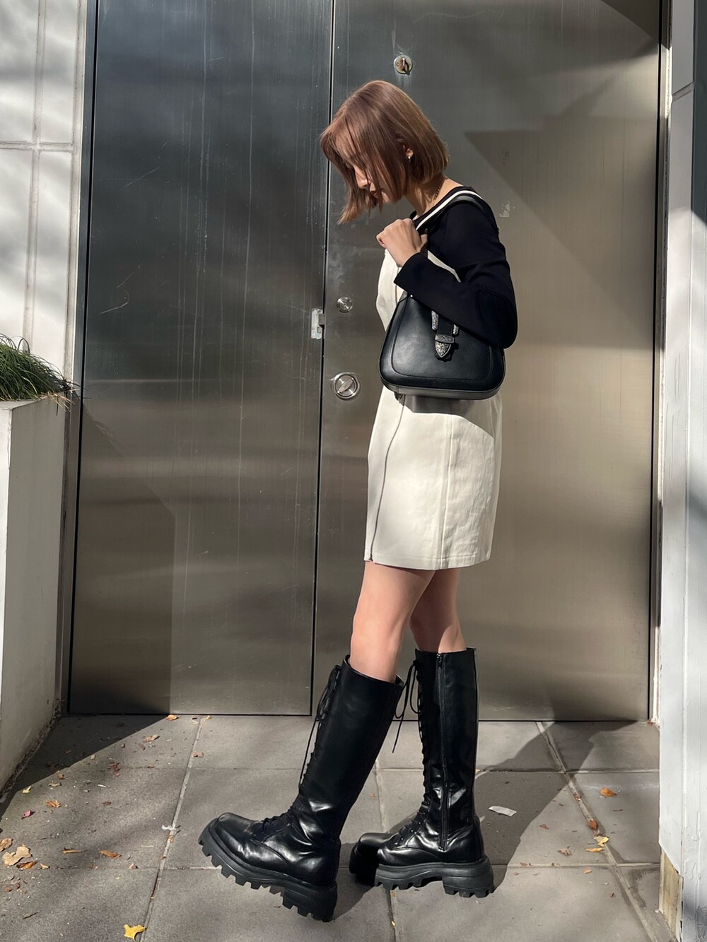 ブラック系のワンピース、ブラック系のハンドバッグ、ブラック系のブーツを着用したレディースの冬コーディネートの2枚目の写真