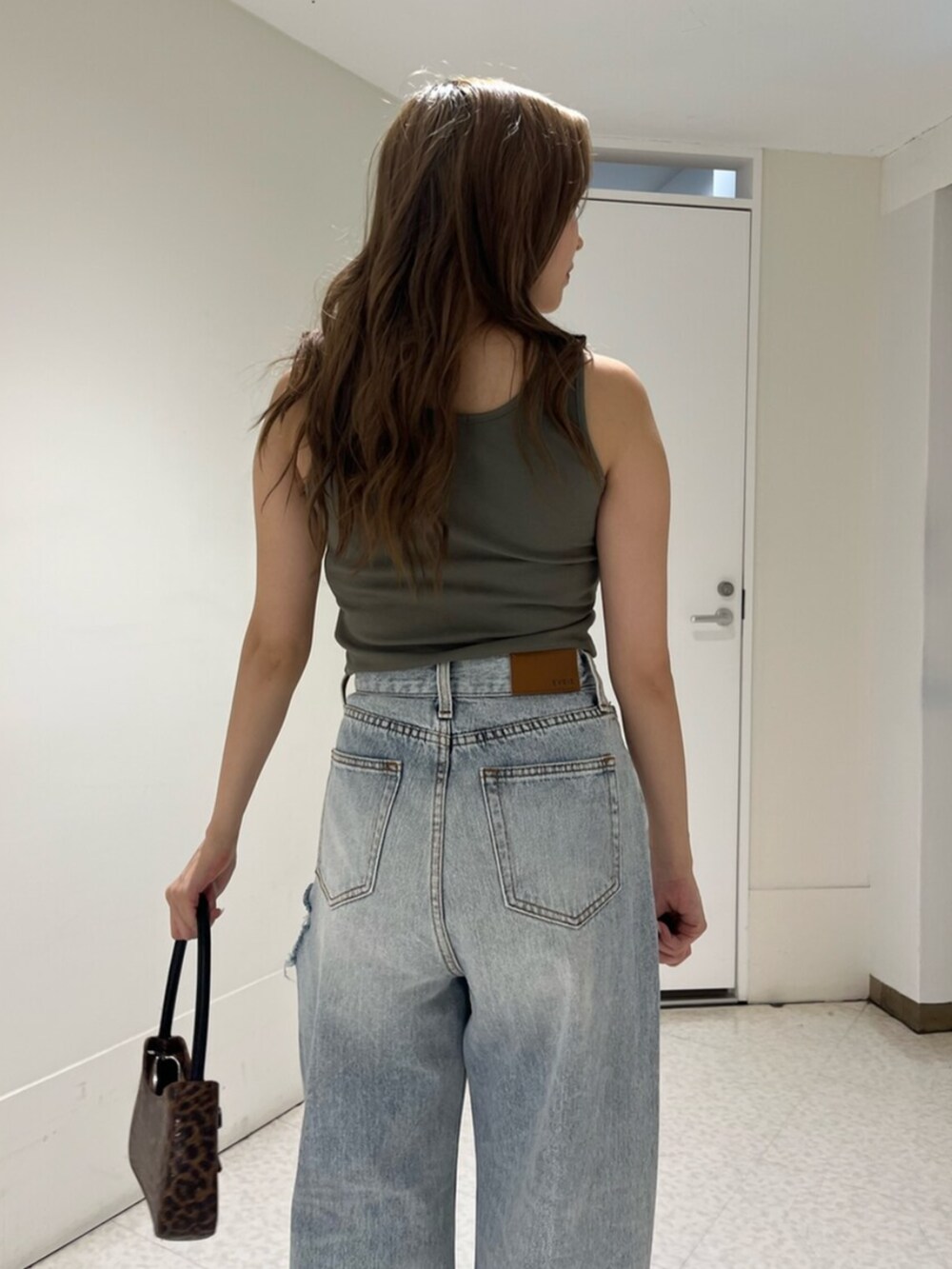 ブラウン系のハンドバッグ、シルバー系のサンダル、ブルー系のデニムパンツを着用したレディースの夏コーディネートの5枚目の写真