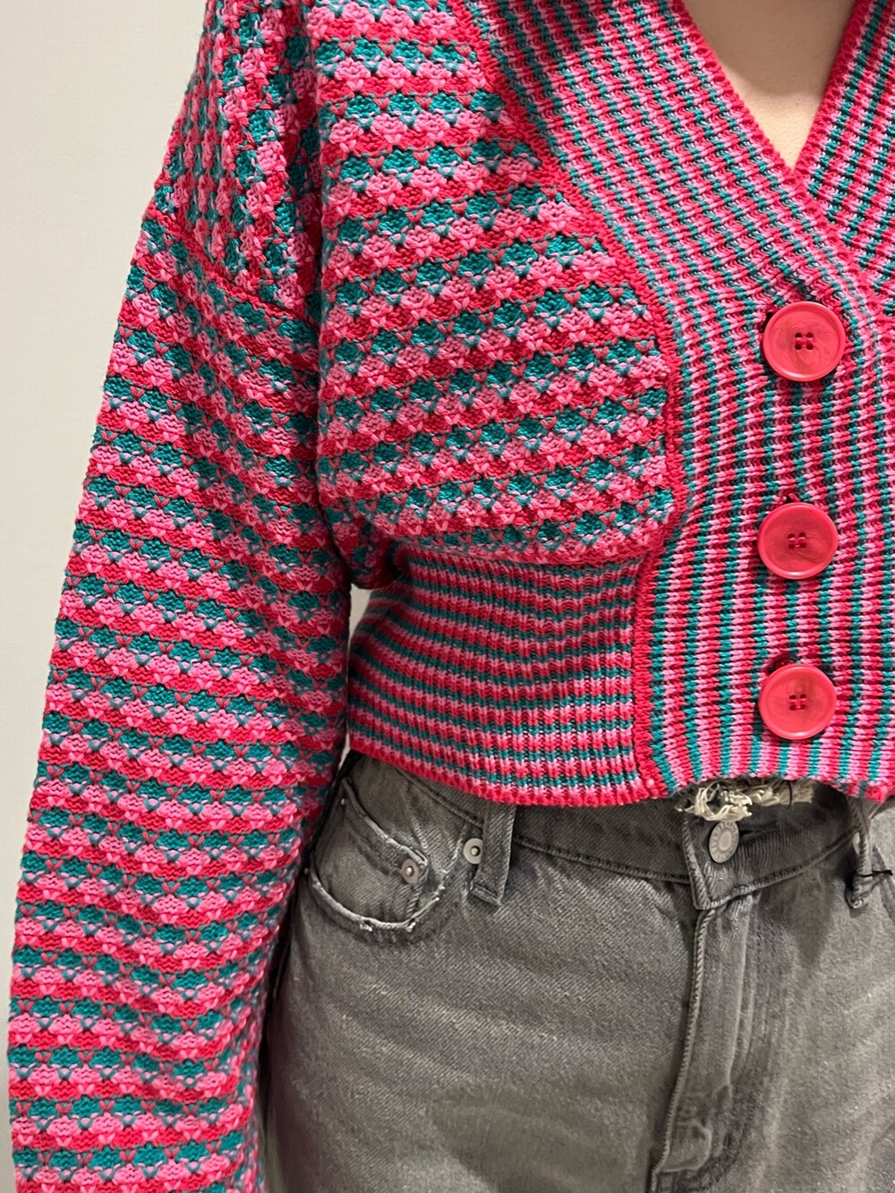 ブラック系のデニムパンツ、ピンク系のカーディガン/ボレロ、ブラック系のブーツを着用したレディースの冬コーディネートの6枚目の写真