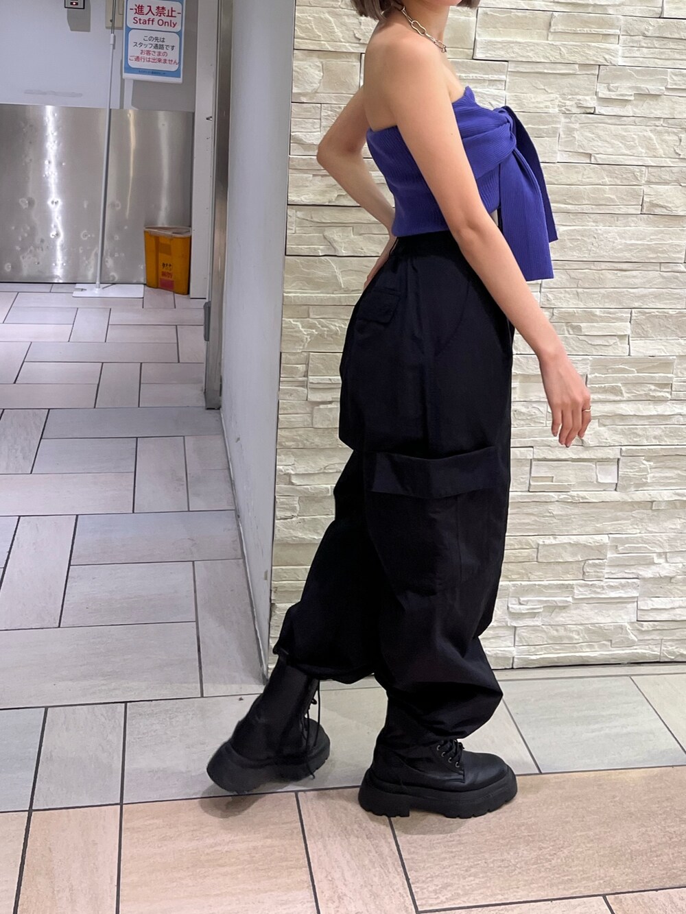 オレンジ系のカーゴパンツ、ブラック系のブーツ、パープル系のチューブトップを着用したレディースの春コーディネートの4枚目の写真