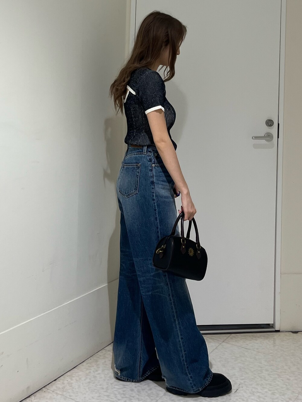 ブラック系のニット/セーター、ブルー系のデニムパンツ、その他のショルダーバッグを着用したレディースの春コーディネートの4枚目の写真