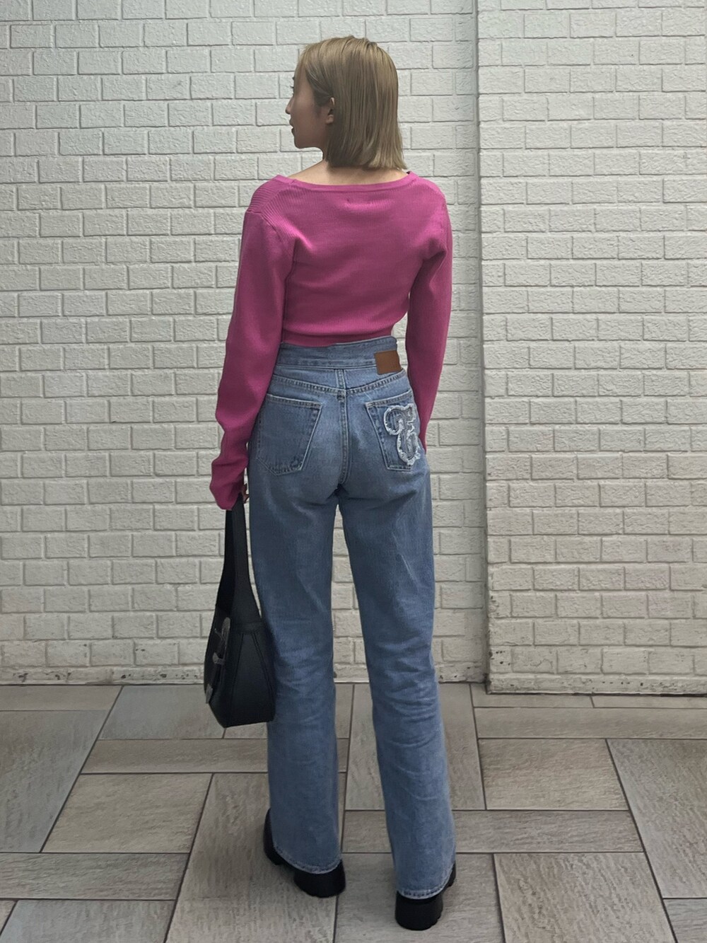 ブルー系のデニムパンツ、ホワイト系のブーツ、ブラック系のハンドバッグを着用したレディースの冬コーディネートの3枚目の写真