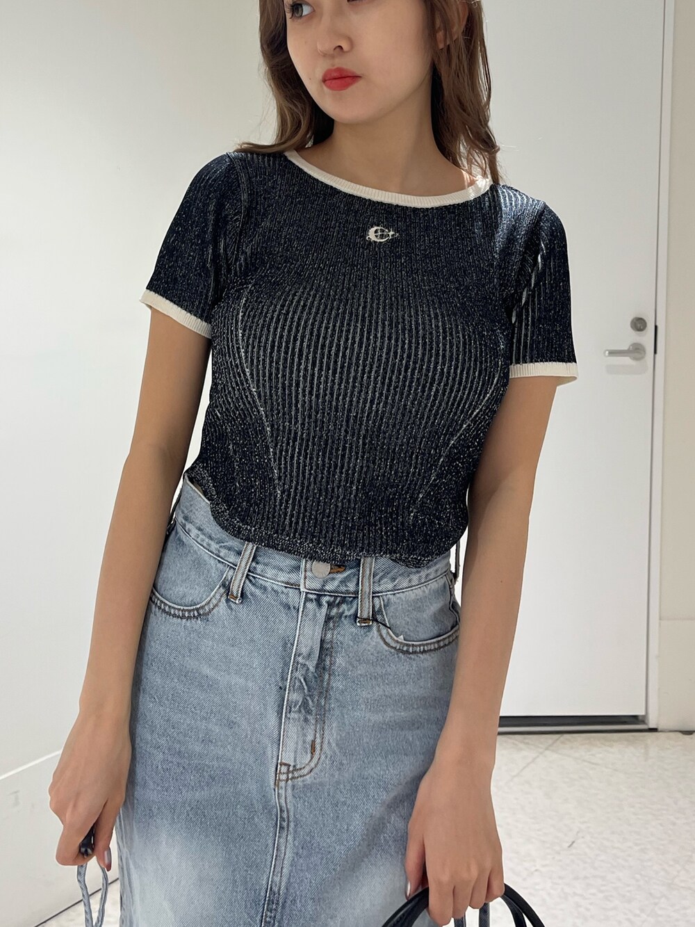 ブラック系のブーツ、ブルー系のデニムスカート、ブラック系のハンドバッグを着用したレディースの春コーディネートの5枚目の写真