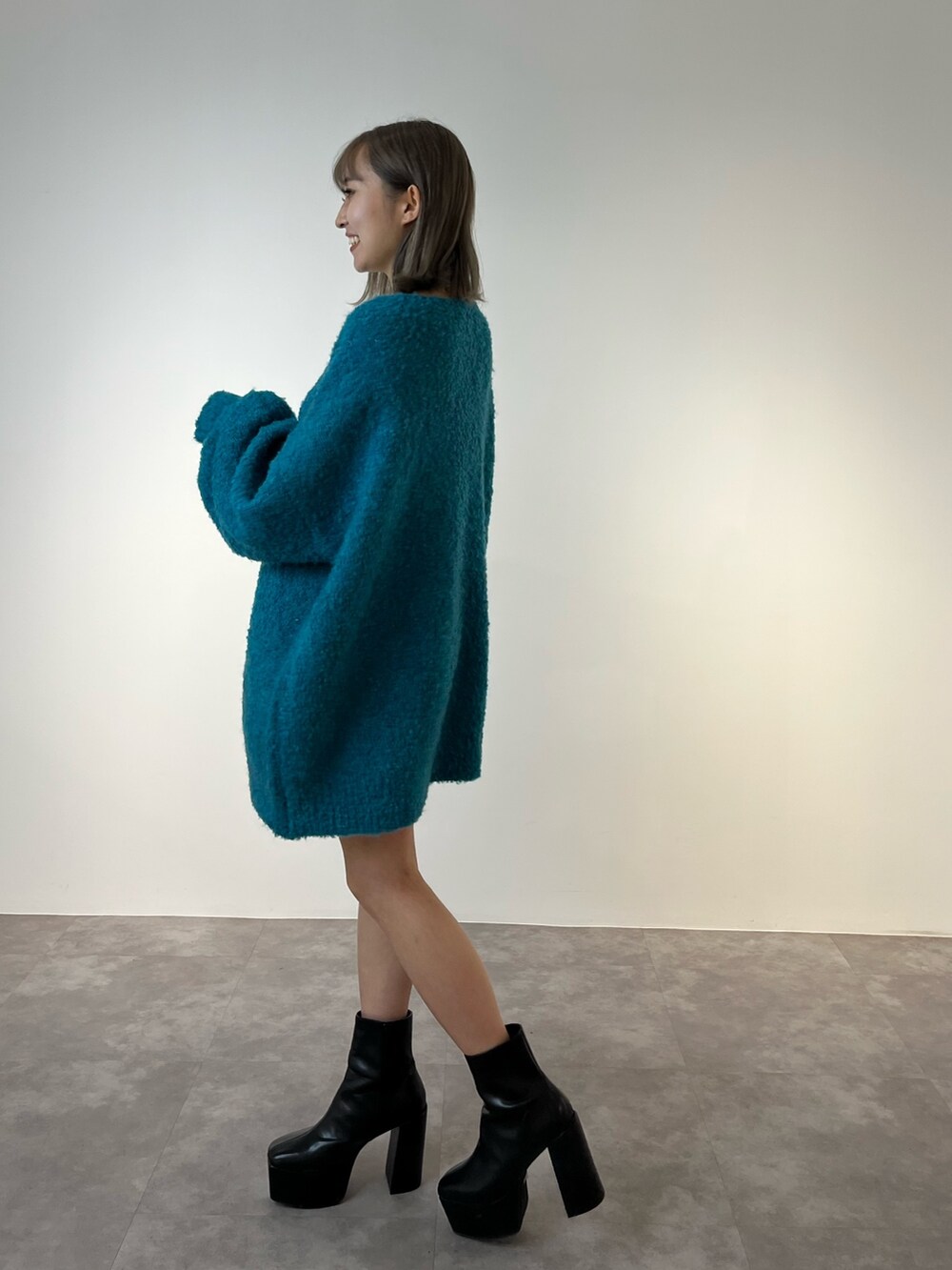 ブルー系のニット/セーター、ブラック系のブーツを着用したレディースの冬コーディネートの2枚目の写真