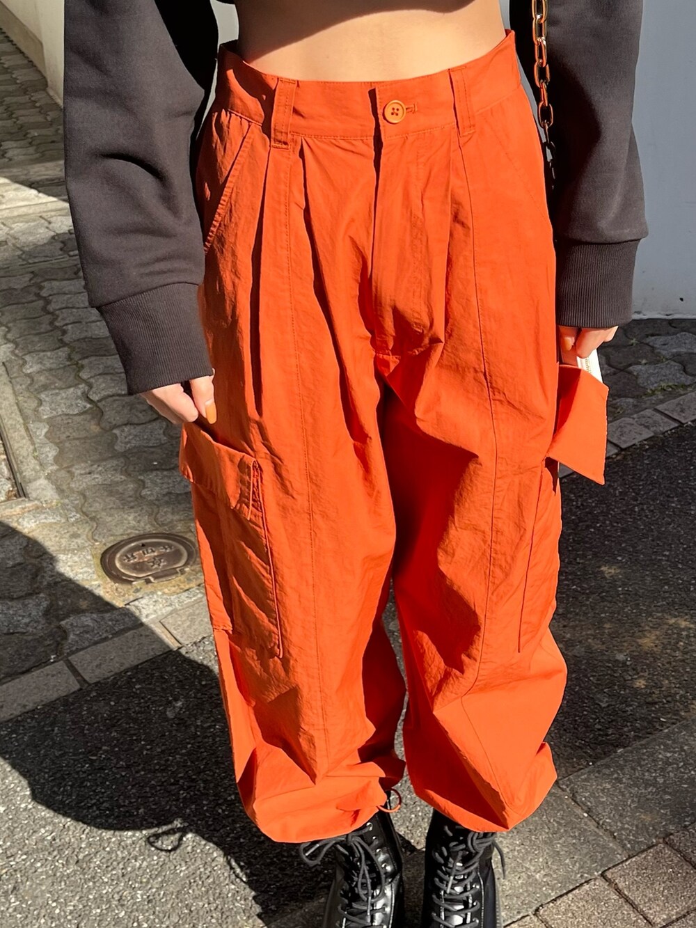 オレンジ系のカーゴパンツ、ホワイト系のブーツ、ブラック系のTシャツ/カットソーを着用したレディースの冬コーディネートの5枚目の写真