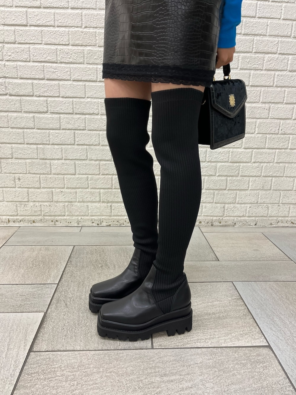 ブラック系のブーツ、ブラック系のワンピース、ブルー系のTシャツ/カットソーを着用したレディースの秋コーディネートの6枚目の写真