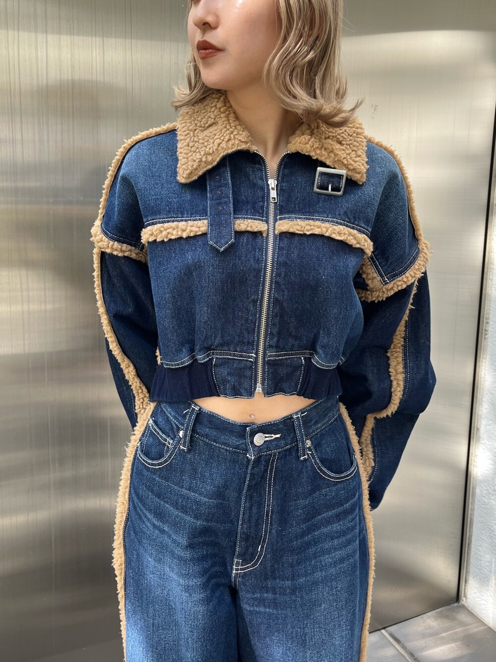 ブラック系のショルダーバッグ、ブラック系のブーツ、ブルー系のデニムパンツを着用したレディースの秋コーディネートの7枚目の写真