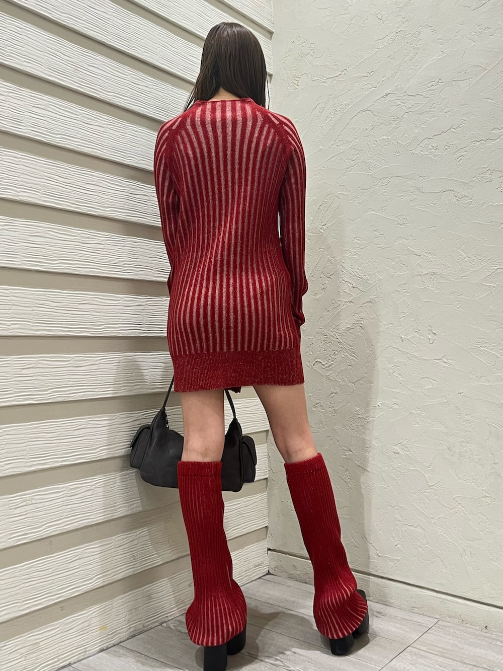 レッド系のワンピース、ブラック系のブーツ、レッド系のレッグウォーマーを着用したレディースの冬コーディネートの3枚目の写真