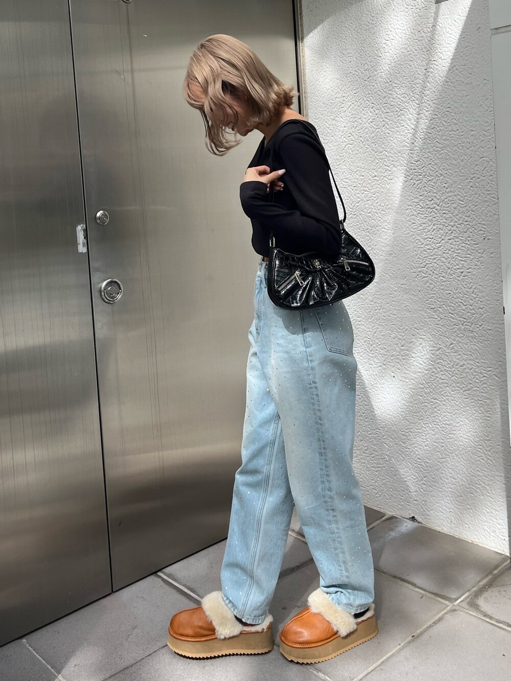 ブラック系のTシャツ/カットソー、ベージュ系のスリッポン、ブルー系のデニムパンツを着用したレディースの秋コーディネートの3枚目の写真