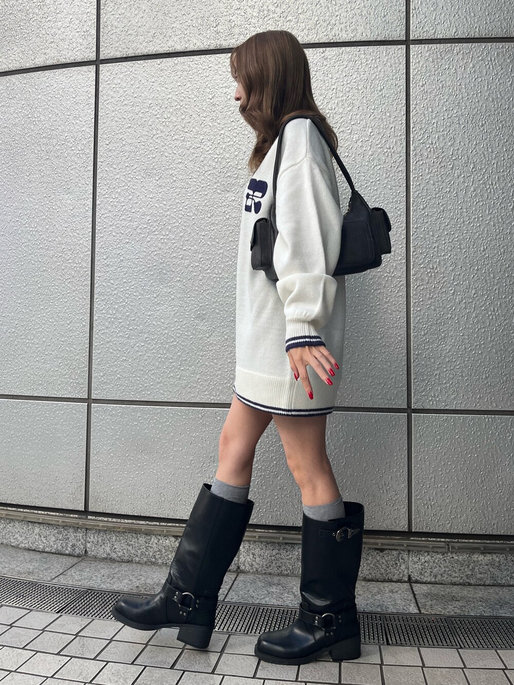 グレー系のハンドバッグ、ブラック系のブーツ、ホワイト系のニット/セーターを着用したレディースの冬コーディネートの2枚目の写真