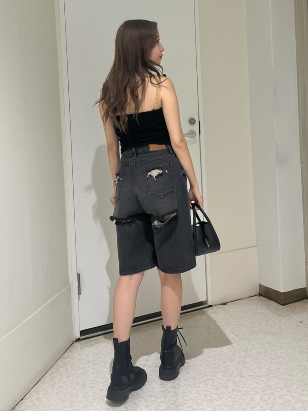 ブラック系のブーツ、ブラック系のハンドバッグ、ブラック系のデニムパンツを着用したレディースの夏コーディネートの3枚目の写真