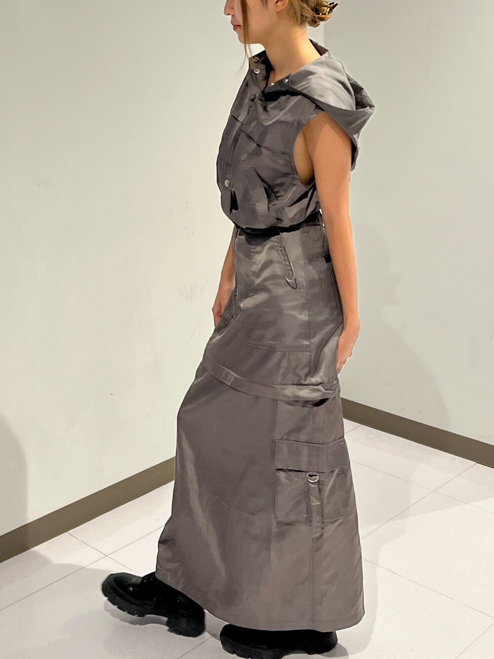 シルバー系のブーツ、グレー系のベスト、ホワイト系のスカートを着用したレディースの夏コーディネートの2枚目の写真