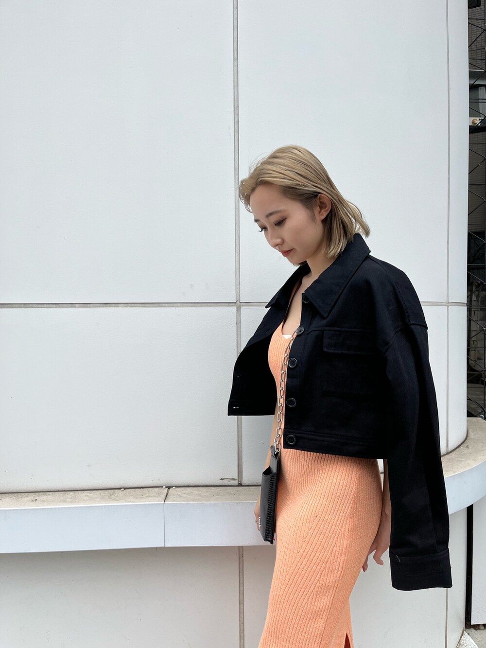 ブラック系のサンダル、ブラック系のミリタリージャケット、オレンジ系のワンピースを着用したレディースの春コーディネートの6枚目の写真