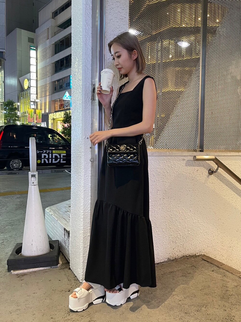 ブラック系のワンピース、ブラック系のショルダーバッグ、ホワイト系のサンダルを着用したレディースの夏コーディネートの2枚目の写真