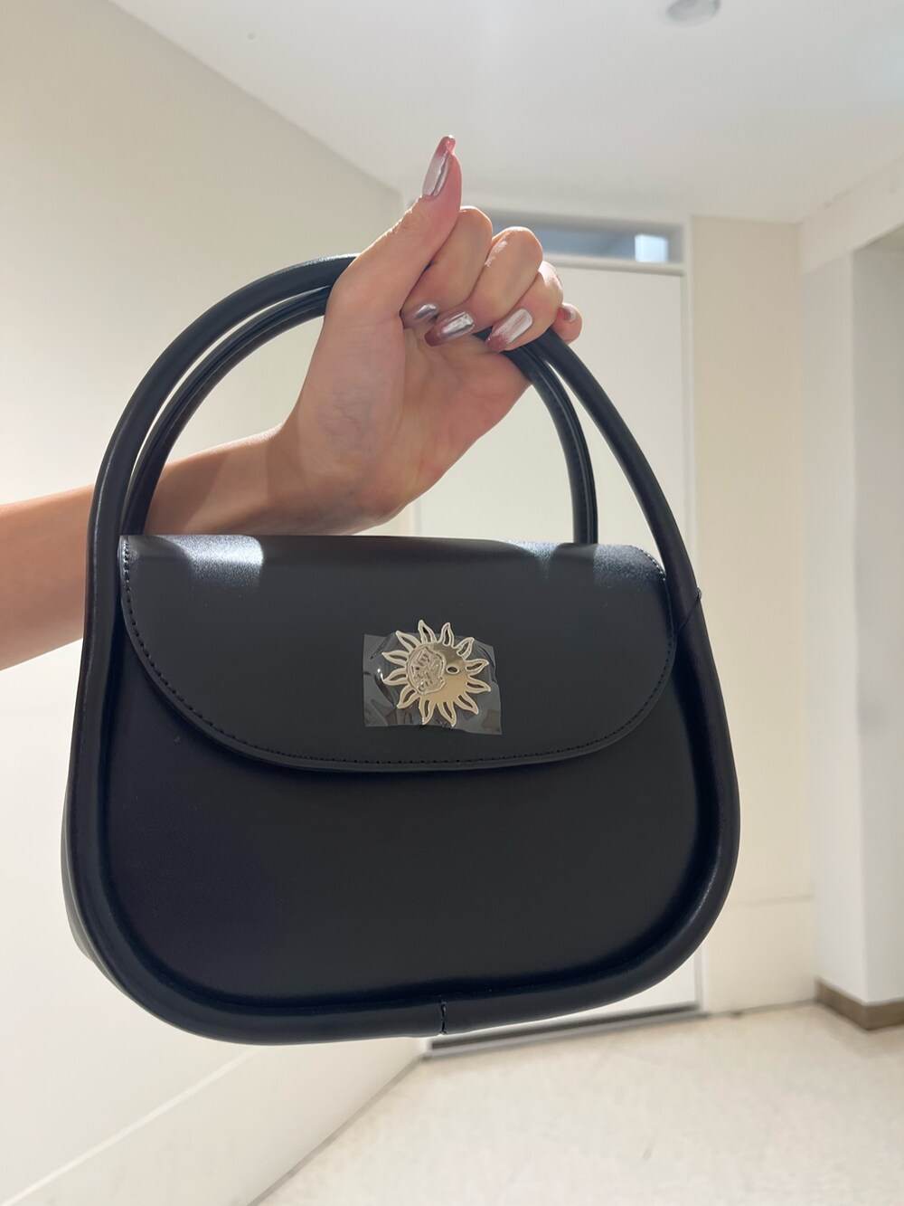 ブラック系のブーツ、ブルー系のデニムスカート、ブラック系のハンドバッグを着用したレディースの春コーディネートの7枚目の写真