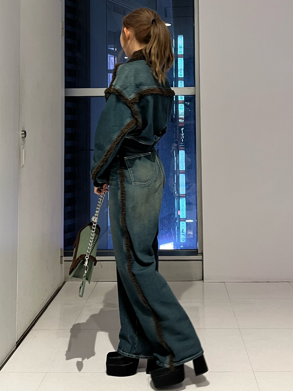 ブルー系のブルゾン、ブルー系のデニムパンツ、ブラック系のブーツを着用したレディースの秋コーディネートの7枚目の写真