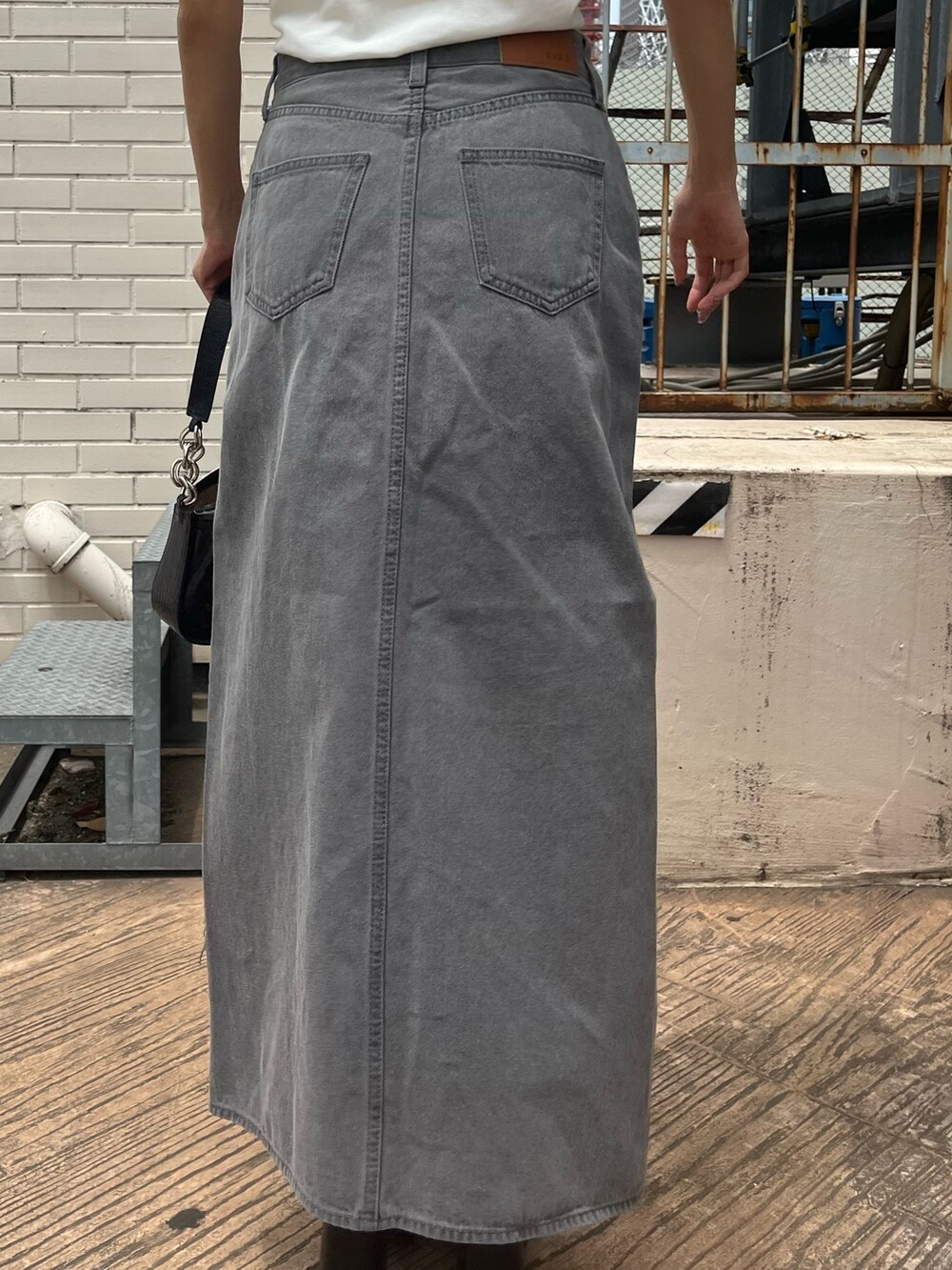 ブラック系のデニムスカート、ブラック系のサンダル、ホワイト系のTシャツ/カットソーを着用したレディースの夏コーディネートの6枚目の写真