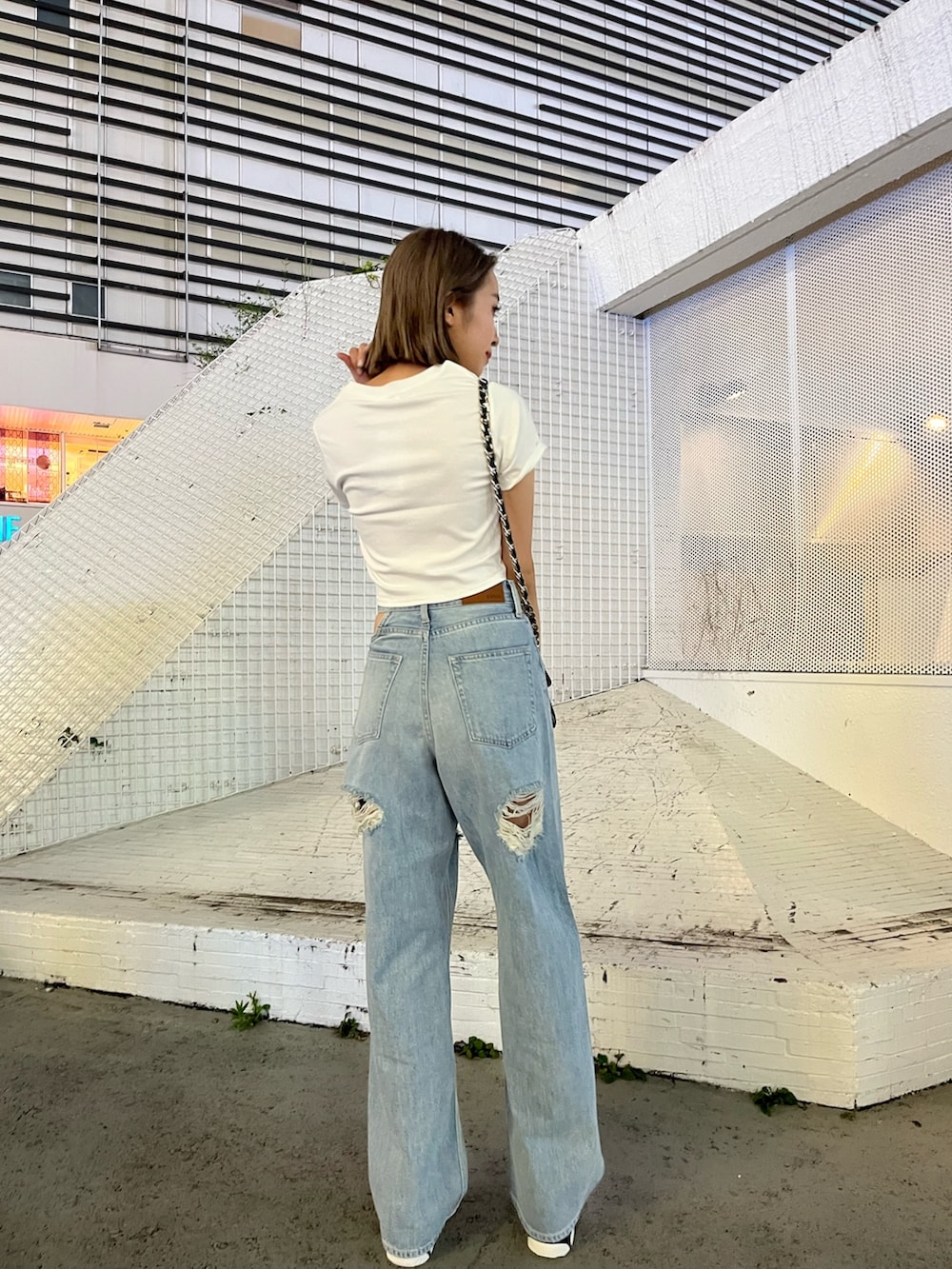 ブルー系のデニムパンツ、ホワイト系のTシャツ/カットソー、ブラック系のショルダーバッグを着用したレディースの夏コーディネートの3枚目の写真