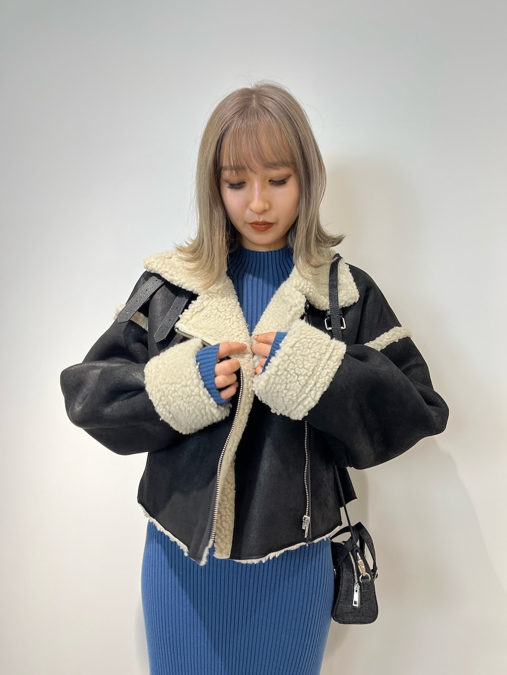 ブラック系のムートンコート、ブルー系のワンピース、ブラック系のブーツを着用したレディースの冬コーディネートの3枚目の写真