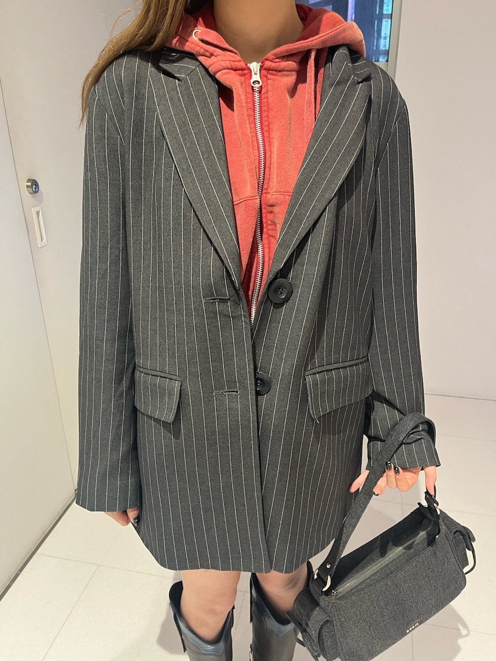 グレー系のテーラードジャケット、グレー系のスカート、レッド系のスウェットを着用したレディースの秋コーディネートの4枚目の写真