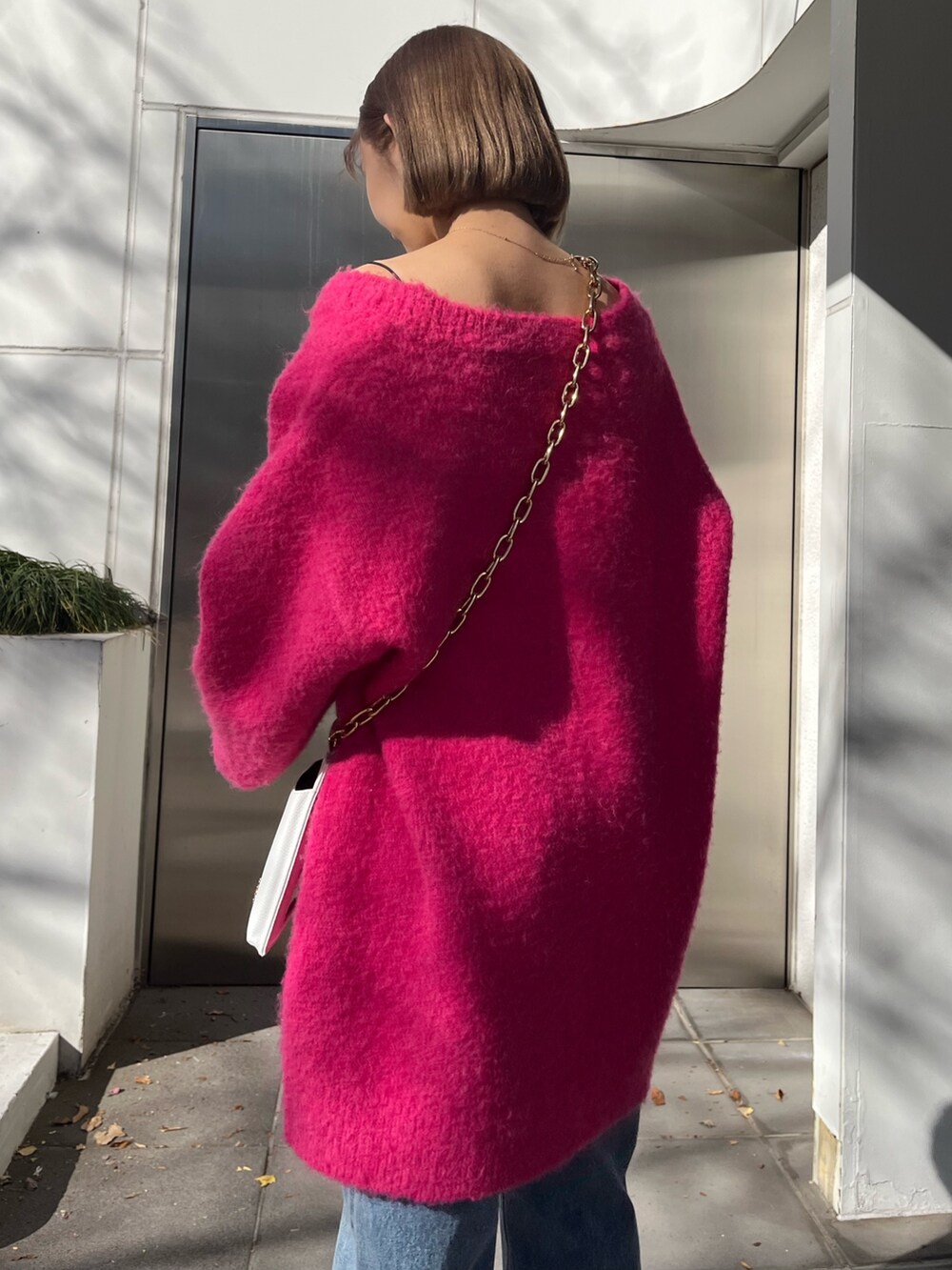 ブルー系のデニムパンツ、ホワイト系のショルダーバッグ、ピンク系のカーディガン/ボレロを着用したレディースの冬コーディネートの8枚目の写真