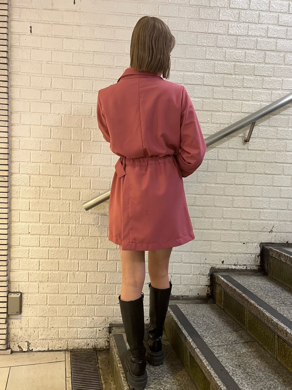 ブラック系のブーツ、ブラック系のショルダーバッグ、ピンク系のワンピースを着用したレディースの冬コーディネートの3枚目の写真