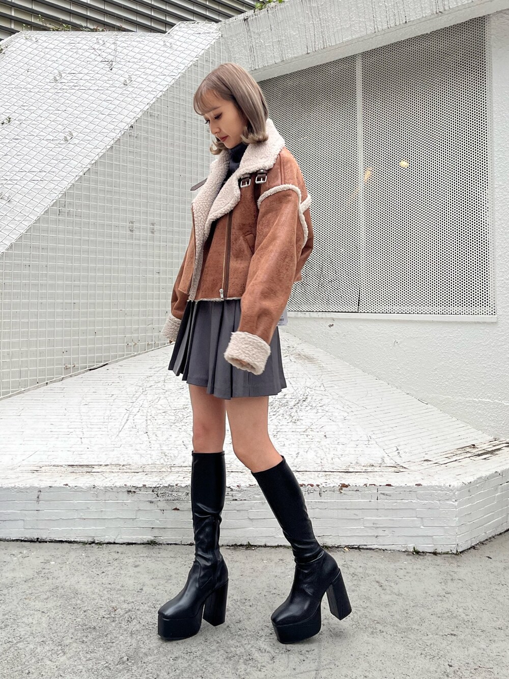 グレー系のスカート、グレー系のTシャツ/カットソー、ブラック系のムートンコートを着用したレディースの秋コーディネートの2枚目の写真